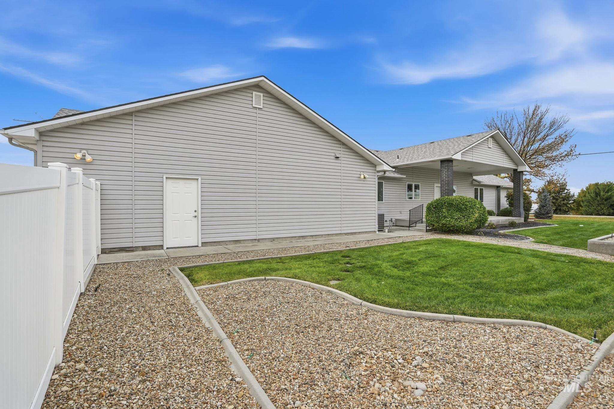 View of side of property featuring a patio, a lawn, and a shingled roof