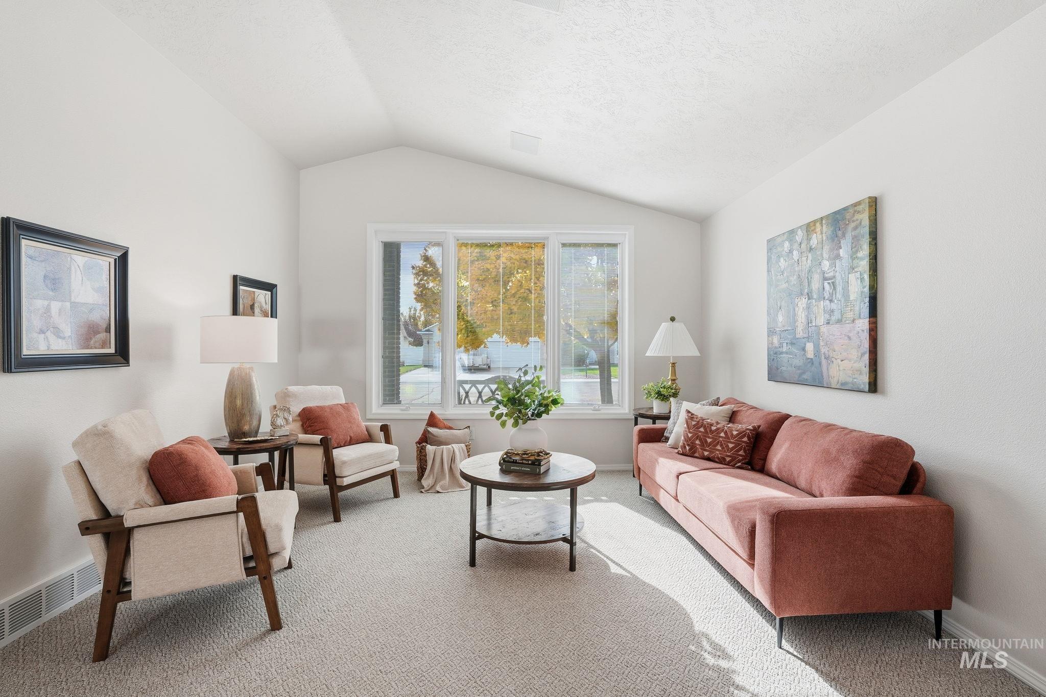 Living room featuring carpet flooring, vaulted ceiling, and a textured ceiling