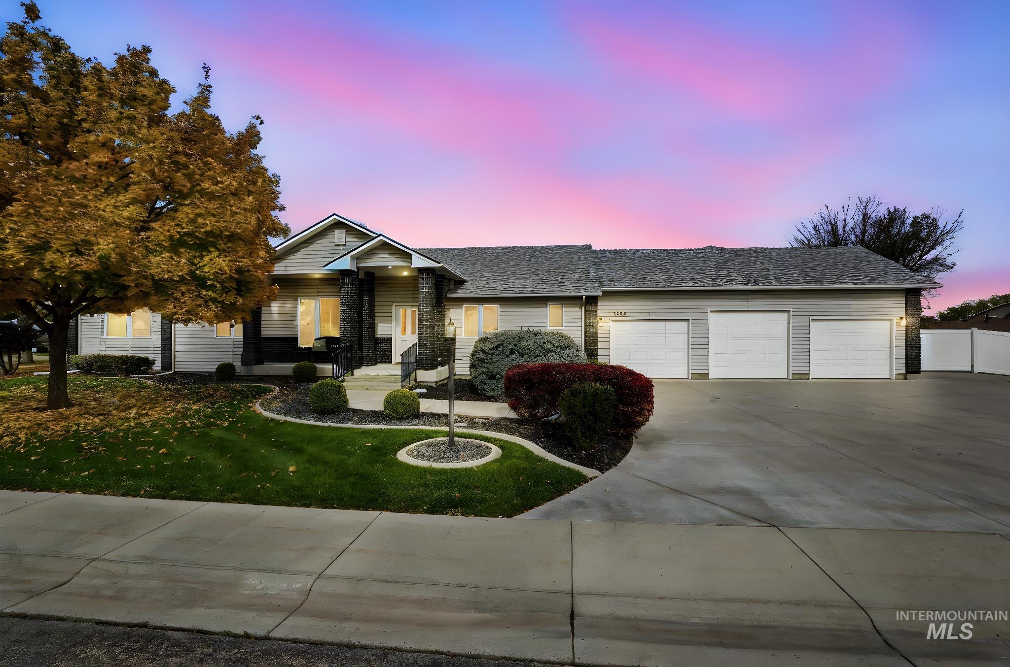 View of front facade featuring concrete driveway, a yard, a garage, a shingled roof, and covered porch