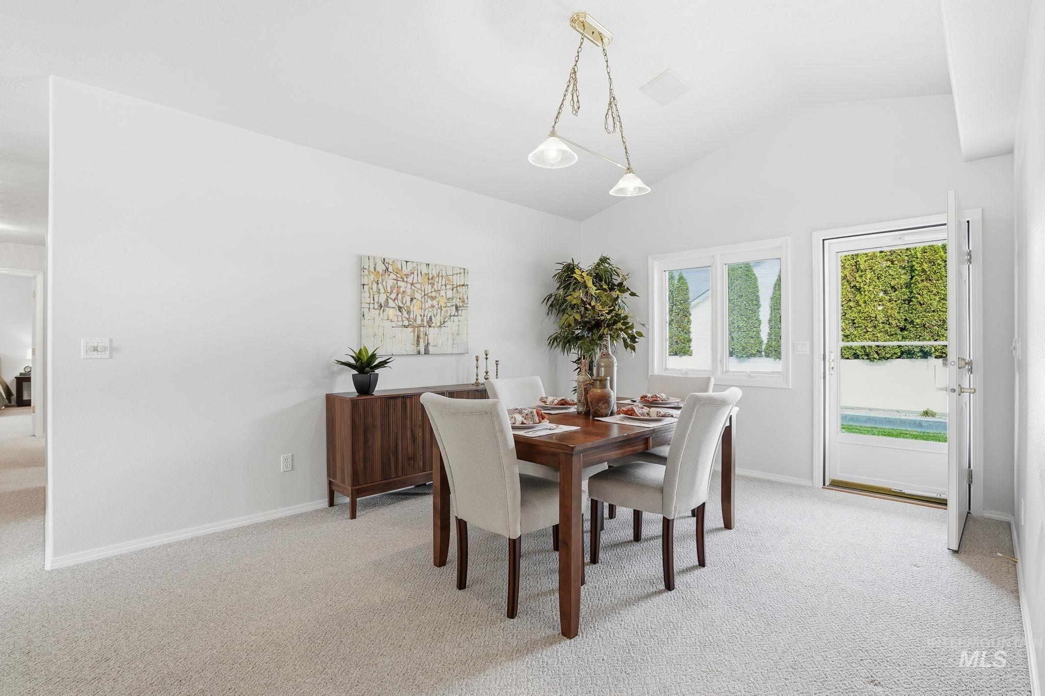 Dining room with light carpet and vaulted ceiling