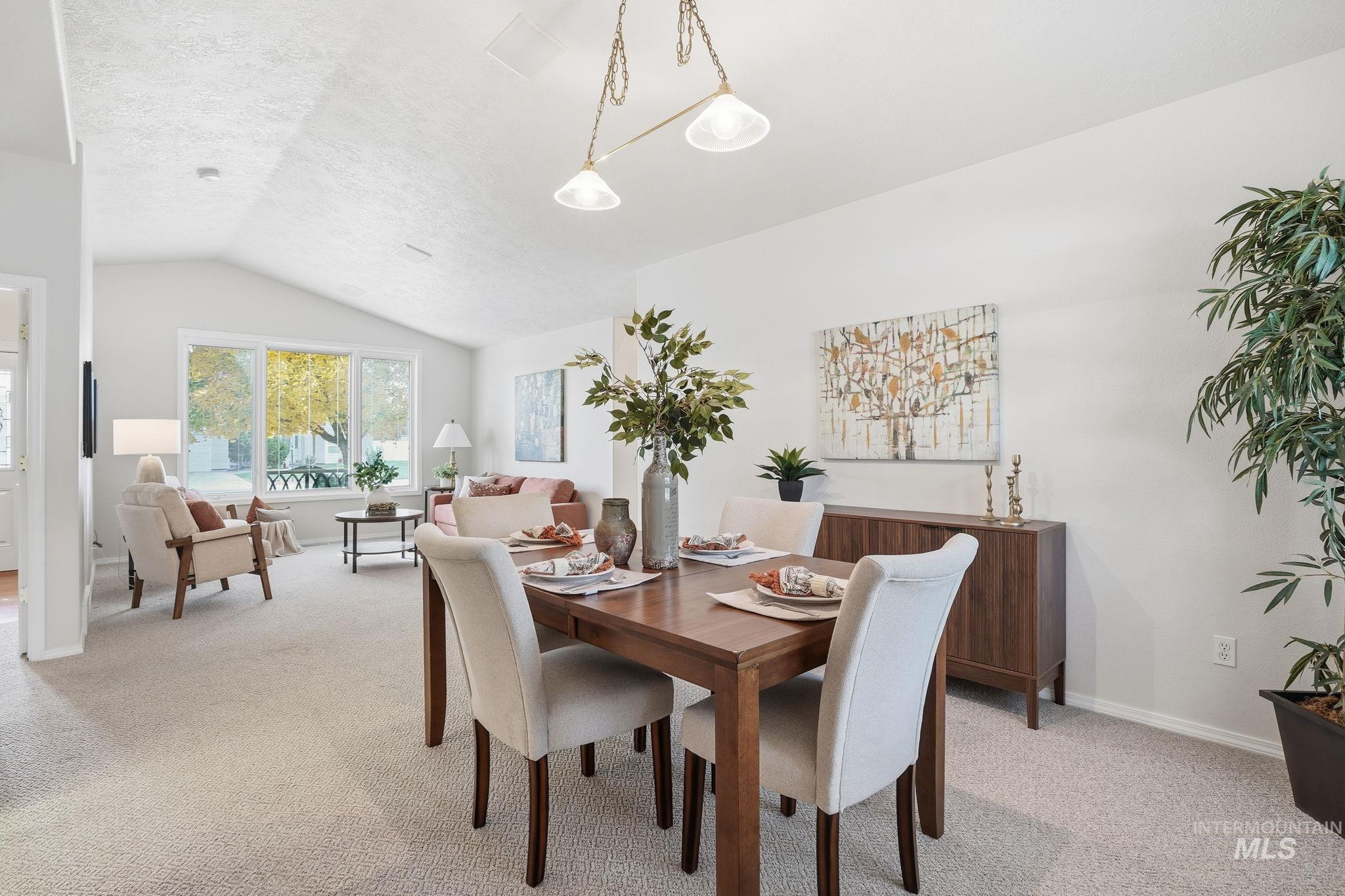 Dining area with light carpet, vaulted ceiling, and a textured ceiling