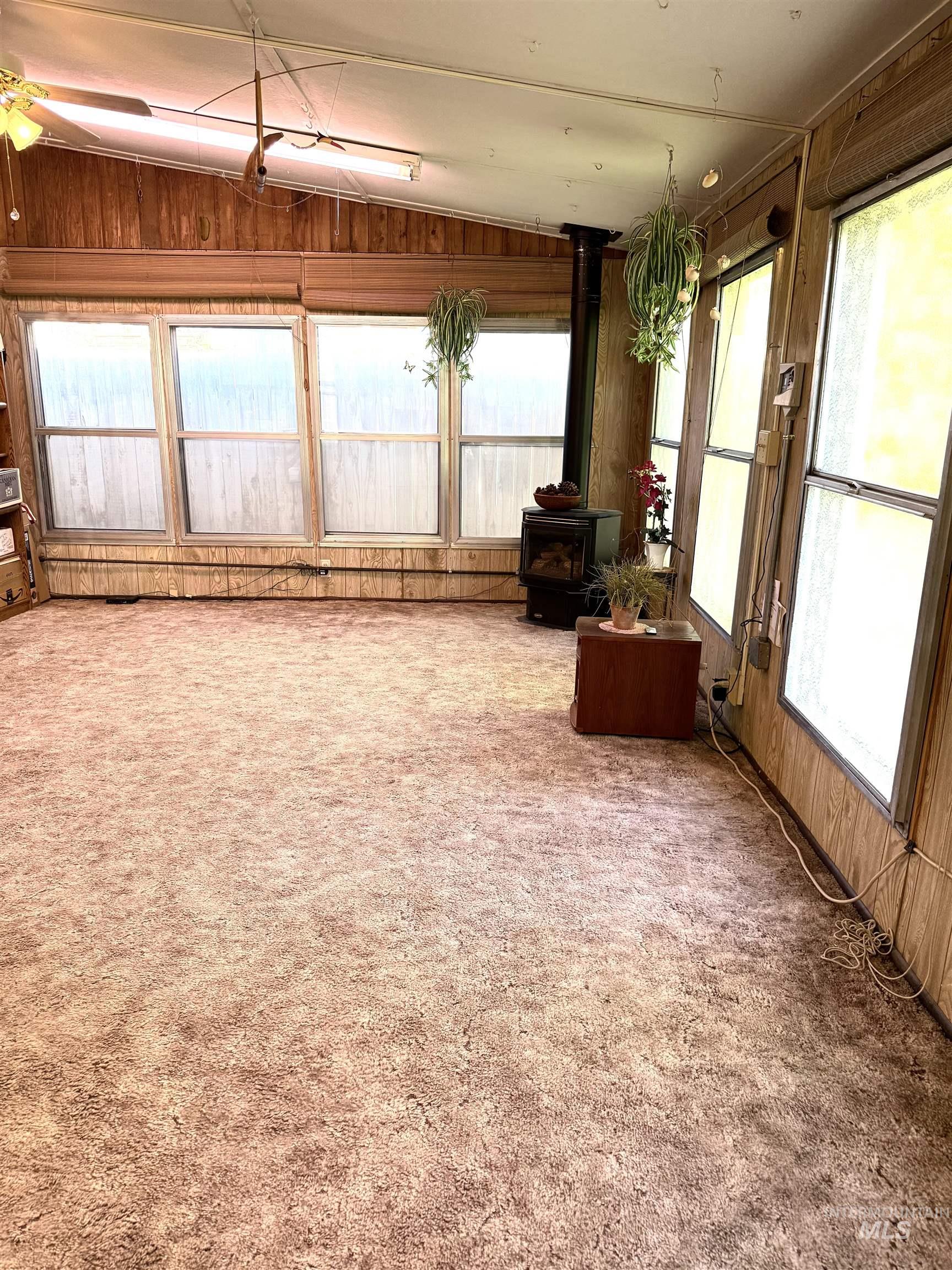Sunroom / solarium with healthy amount of natural light, a wood stove, and lofted ceiling