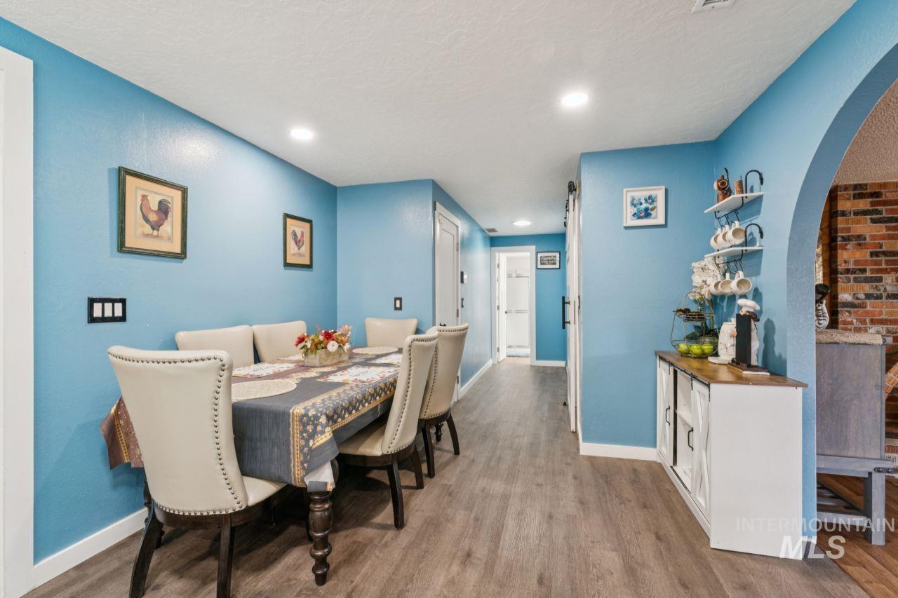 Dining room featuring arched walkways, wood finished floors, recessed lighting, and a textured ceiling