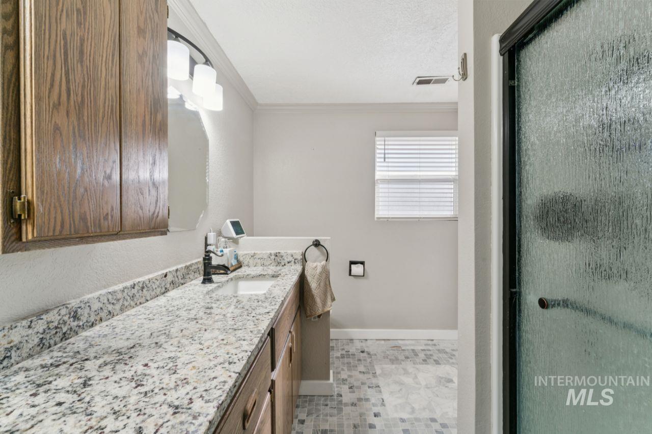 Bathroom with vanity, a textured ceiling, a stall shower, light tile patterned floors, and crown molding