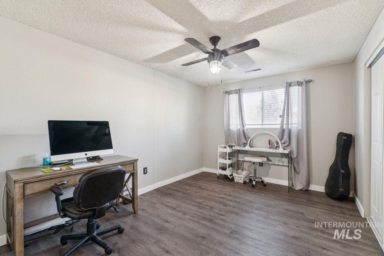 Office space with a textured ceiling, dark wood-style flooring, and a ceiling fan