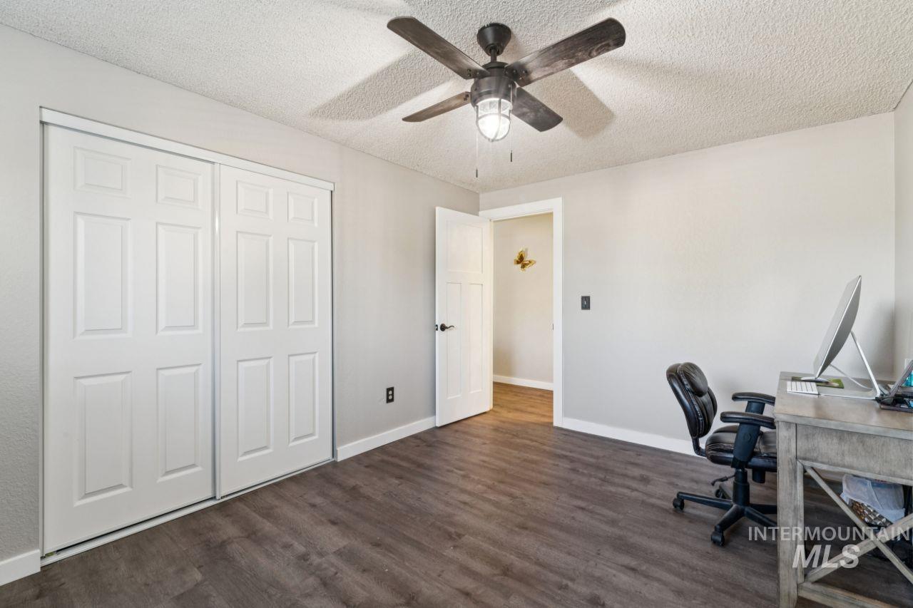 Office space with a textured ceiling, dark wood finished floors, and a ceiling fan