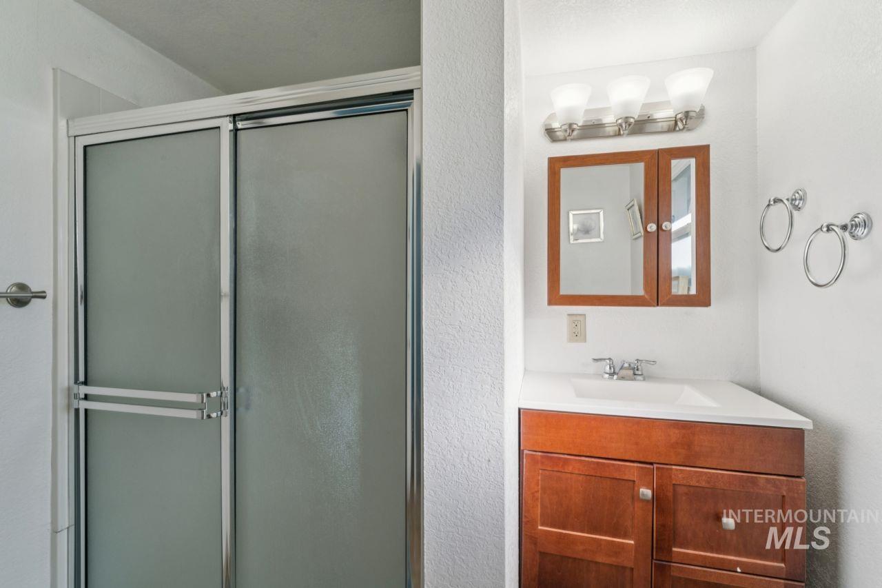Full bath featuring vanity, a stall shower, and a textured wall