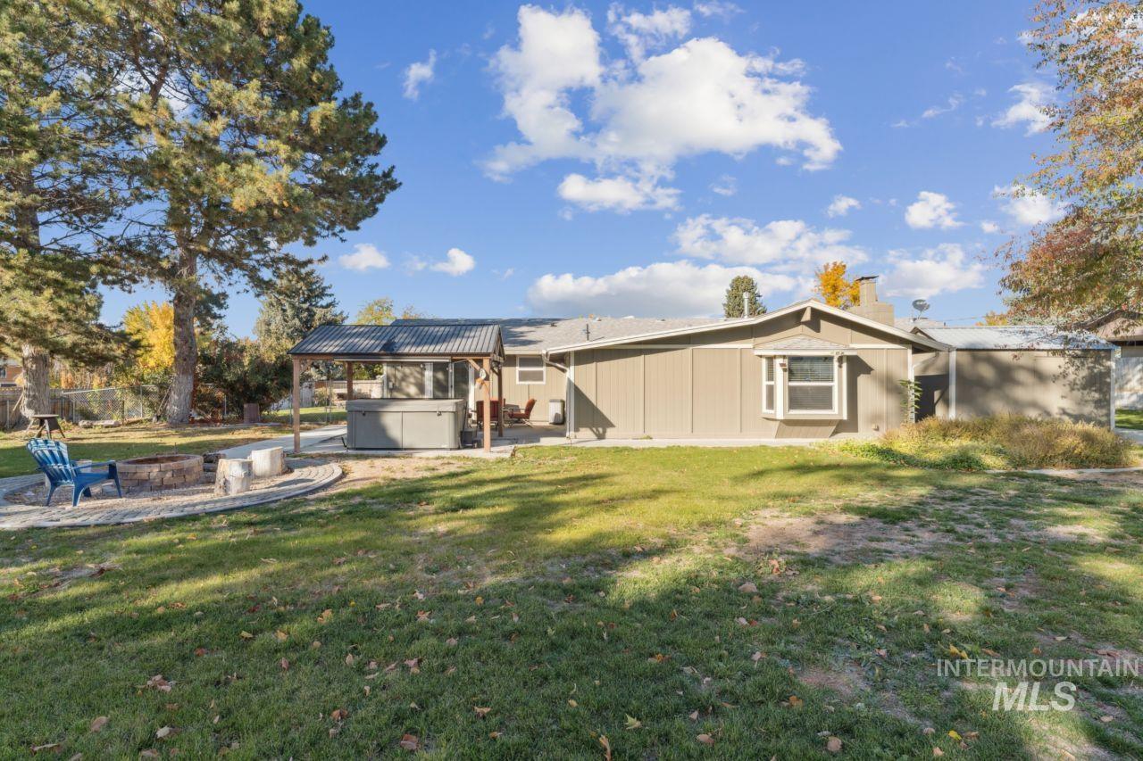 Rear view of house with a hot tub, a patio area, a fire pit, a chimney, and a metal roof