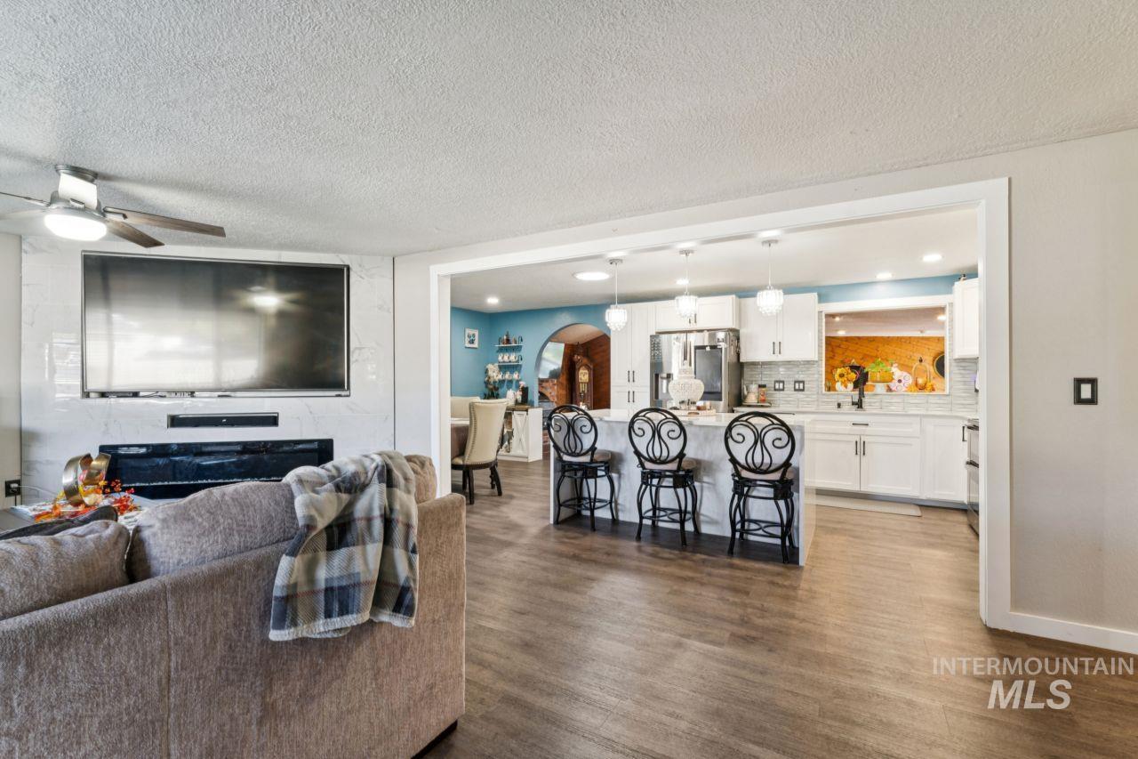 Living room with arched walkways, dark wood-style flooring, a ceiling fan, and a textured ceiling