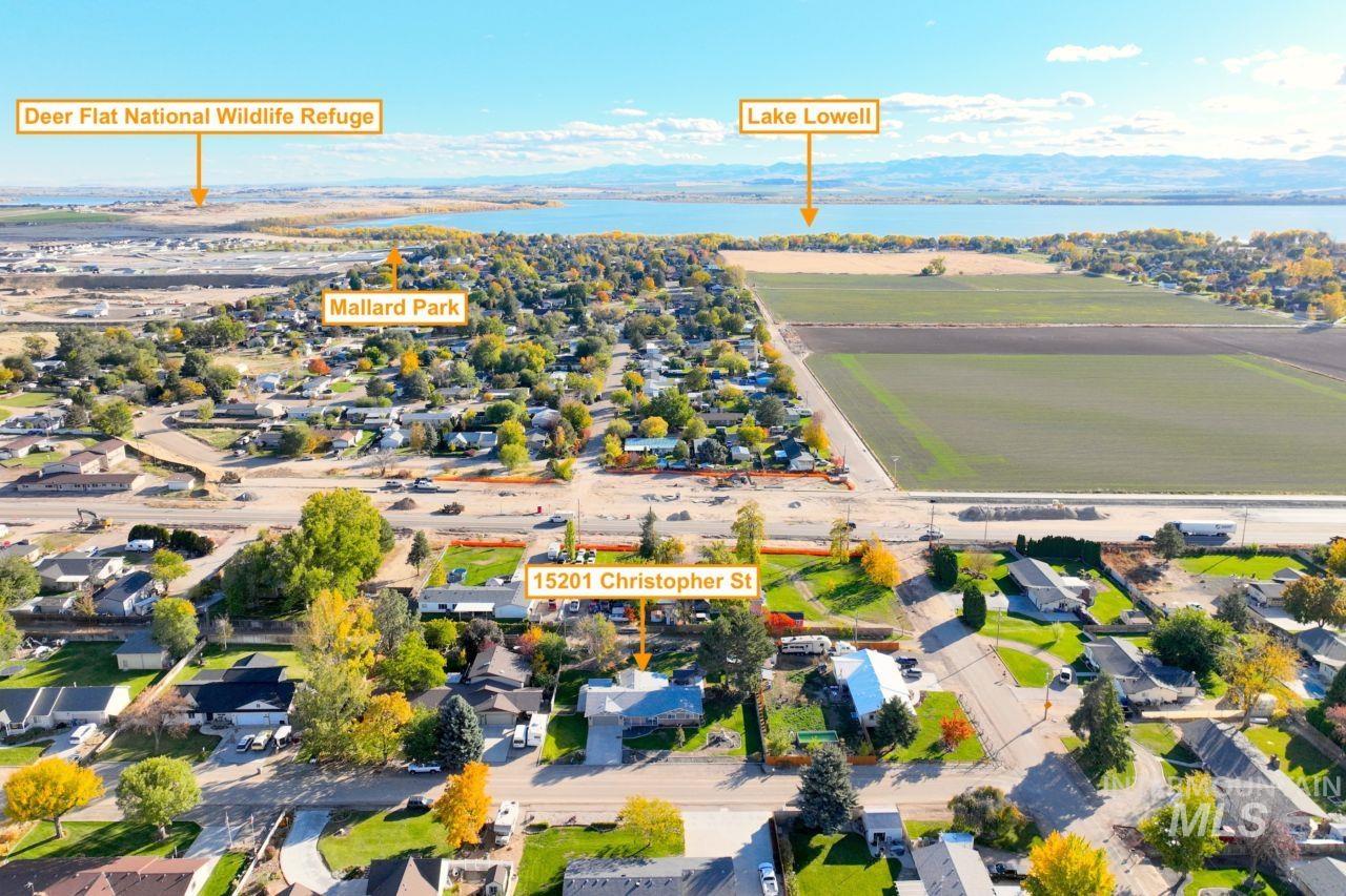 Aerial view of property and surrounding area featuring nearby suburban area and a large body of water