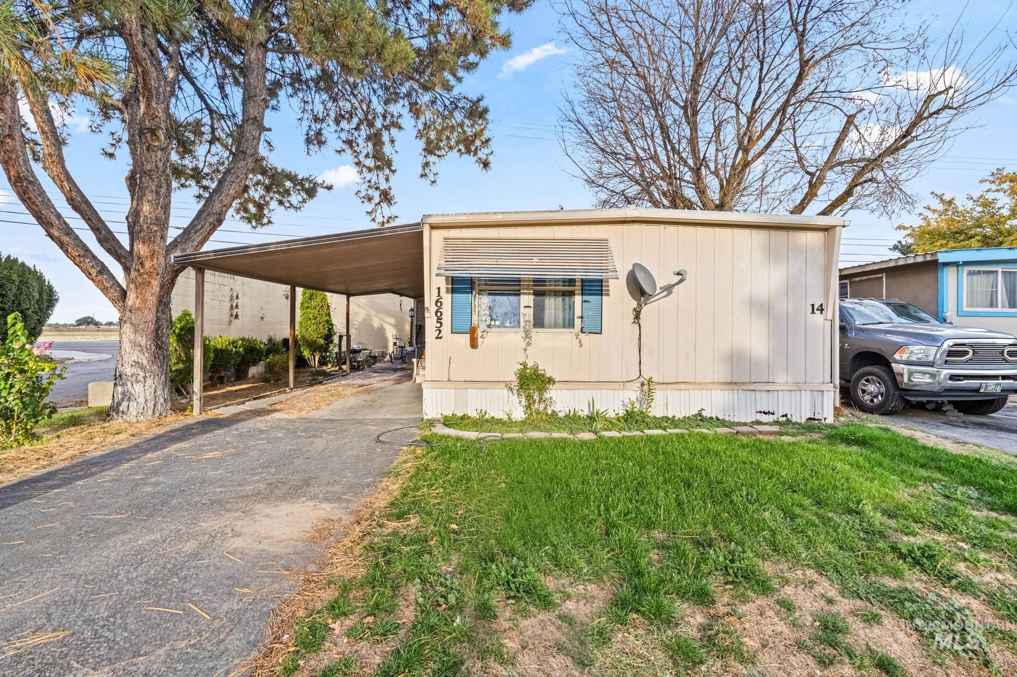 Manufactured / mobile home with a front yard, driveway, and an attached carport