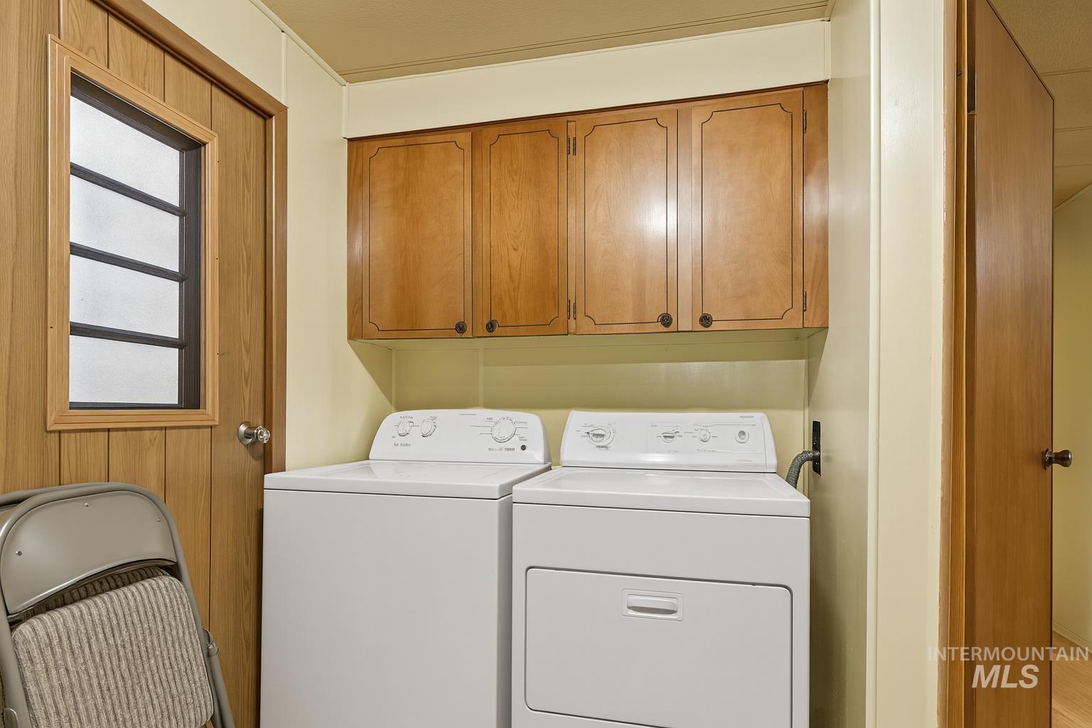 Washroom with cabinet space and washing machine and clothes dryer
