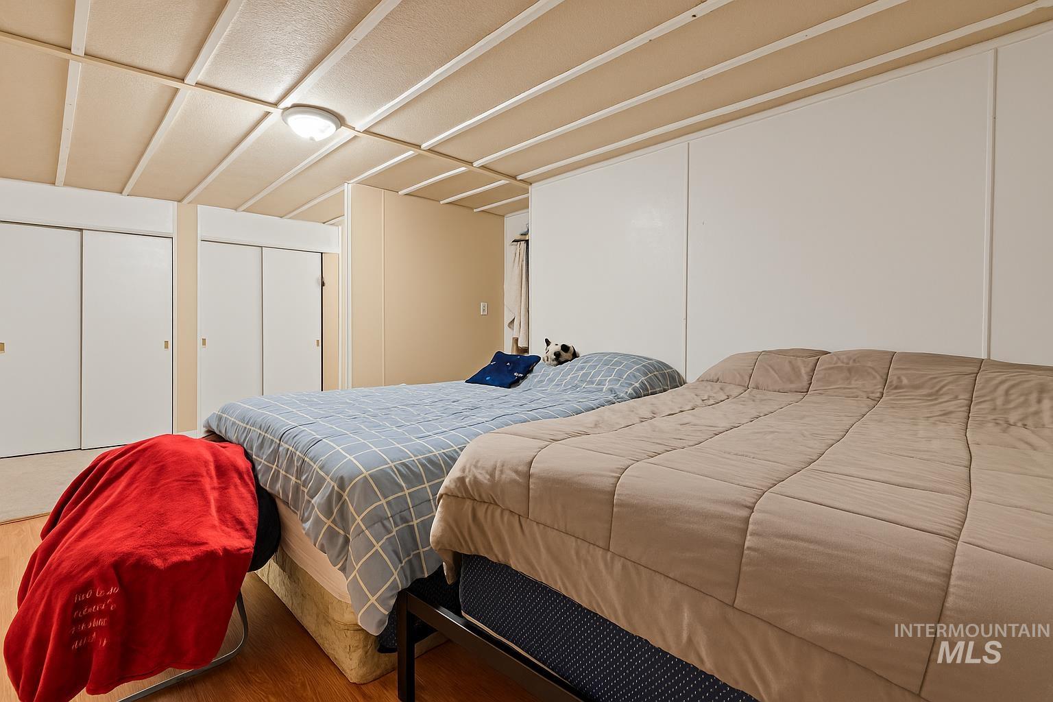 Bedroom with multiple closets and wood finished floors