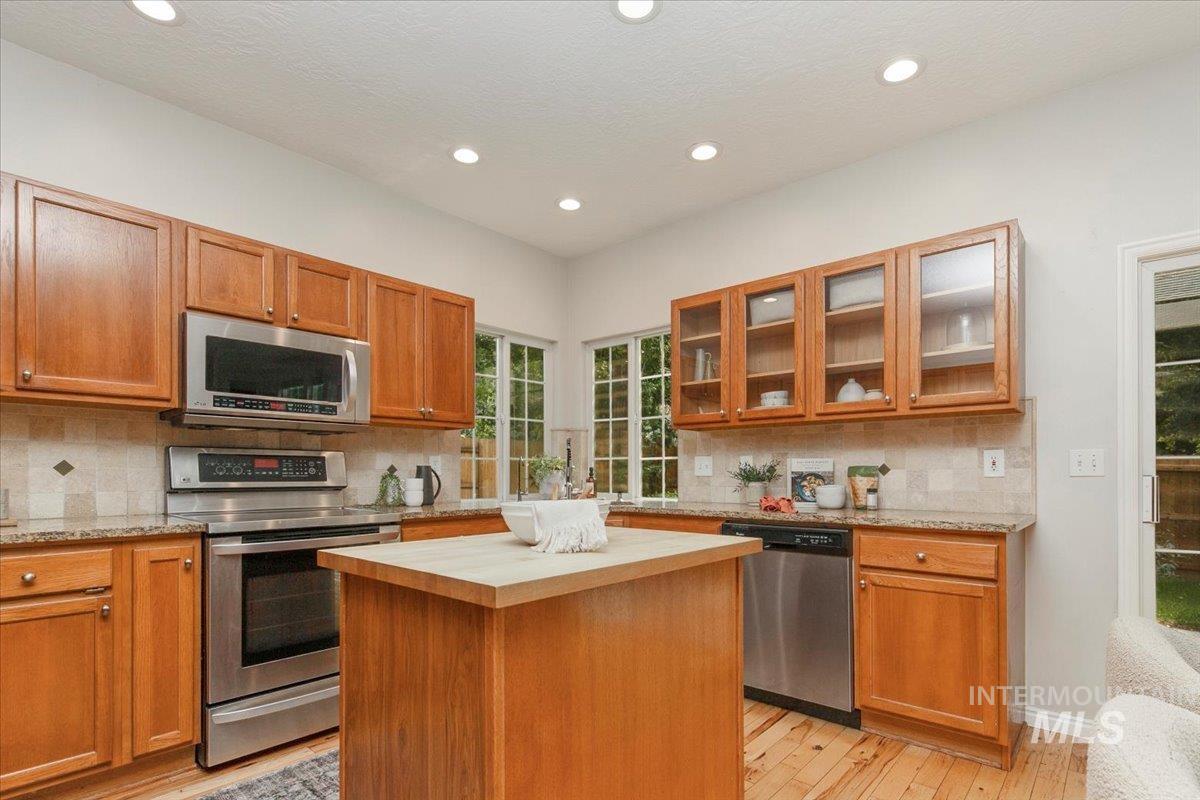 Kitchen featuring appliances with stainless steel finishes, brown cabinetry, decorative backsplash, and recessed lighting