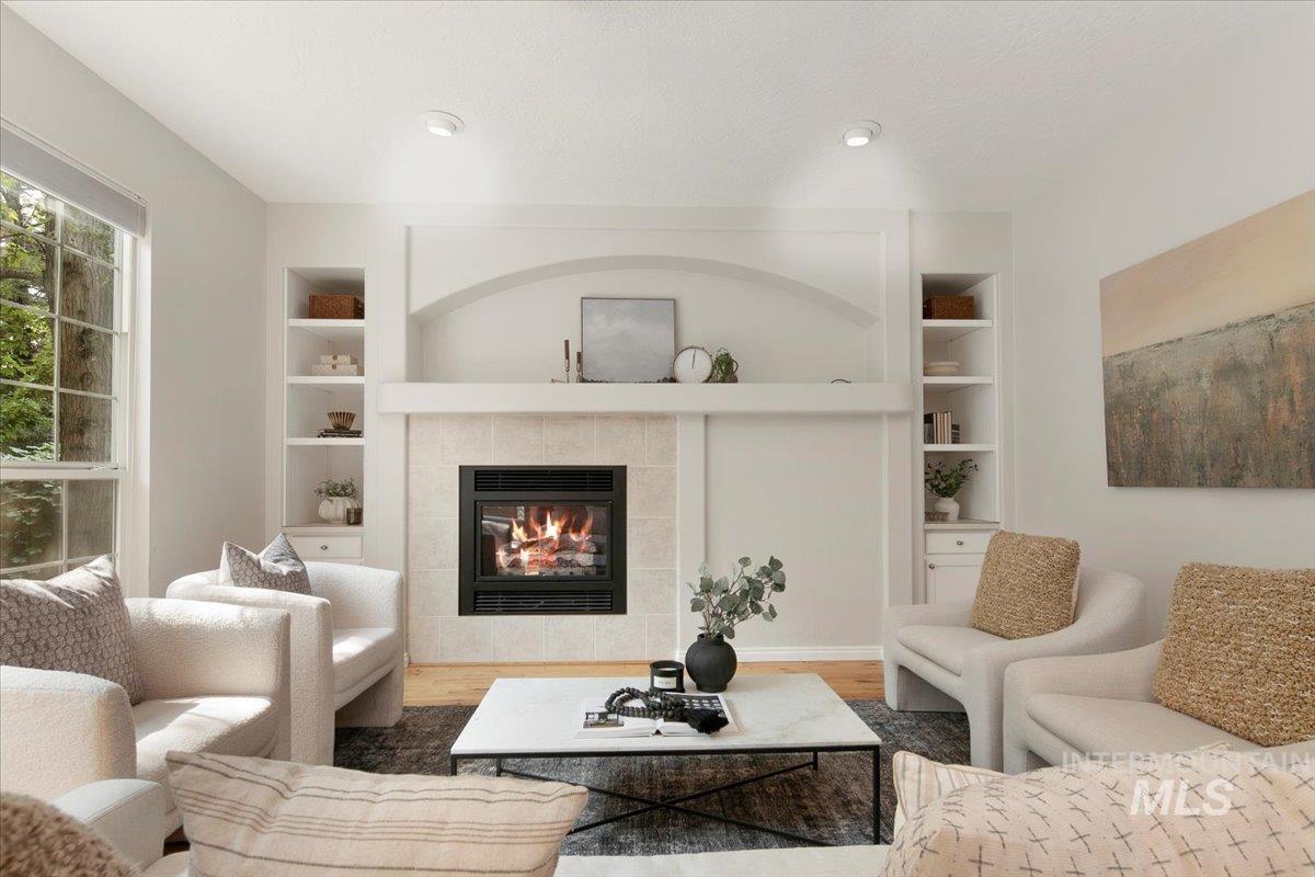 Living room with built in shelves, a fireplace, and wood finished floors