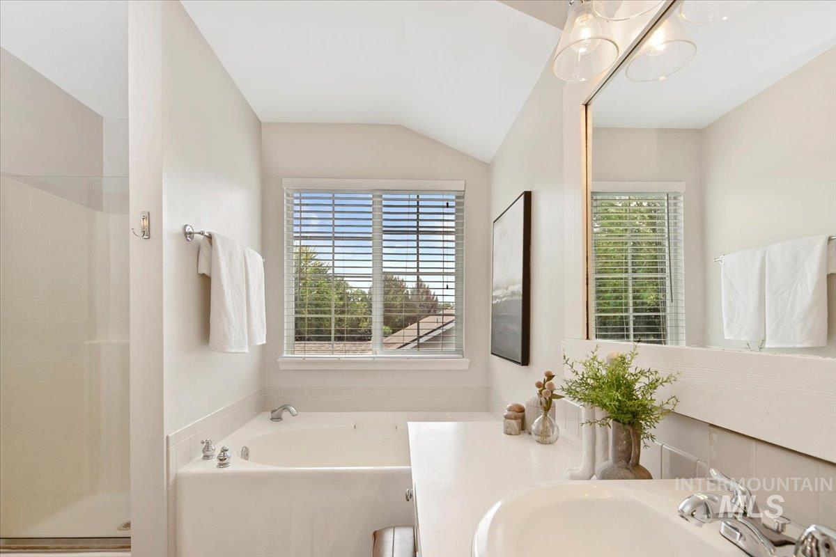 Bathroom with plenty of natural light, a garden tub, vanity, lofted ceiling, and a shower stall