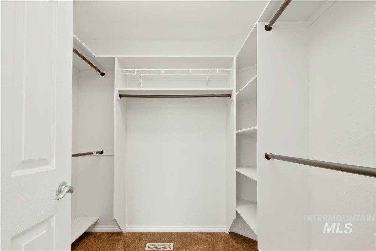 Spacious closet featuring dark colored carpet