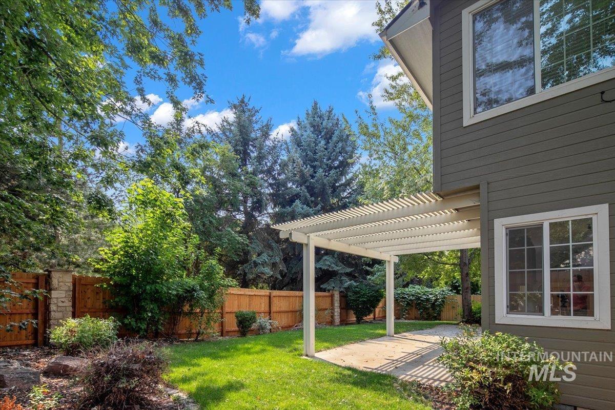 Fenced backyard with a pergola, a patio area, and view of scattered trees
