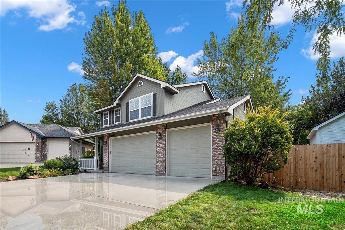 Traditional-style house with concrete driveway, an attached garage, brick siding, a shingled roof, and covered porch