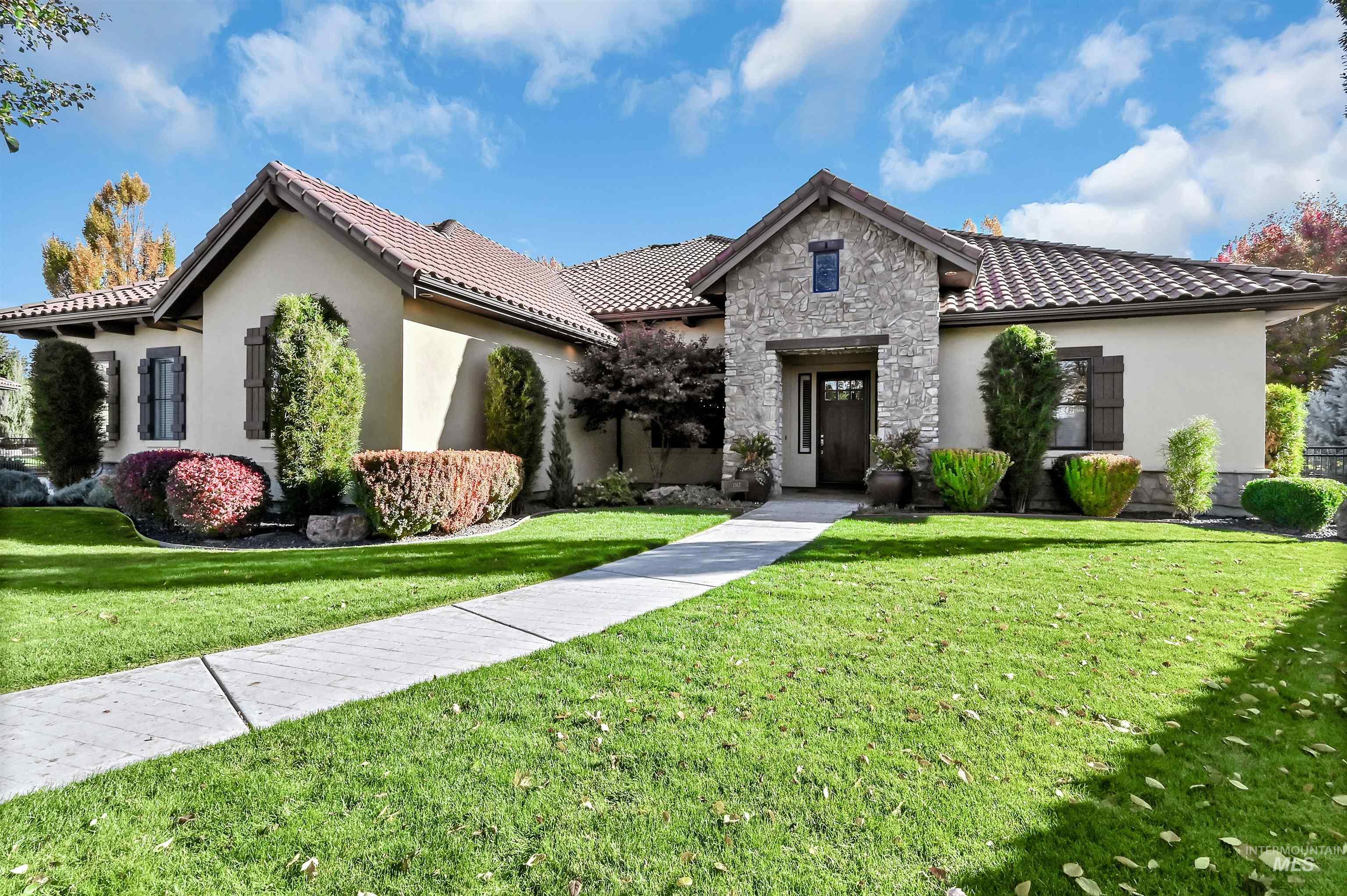 Mediterranean / spanish home featuring stucco siding, stone siding, a front yard, and a tiled roof