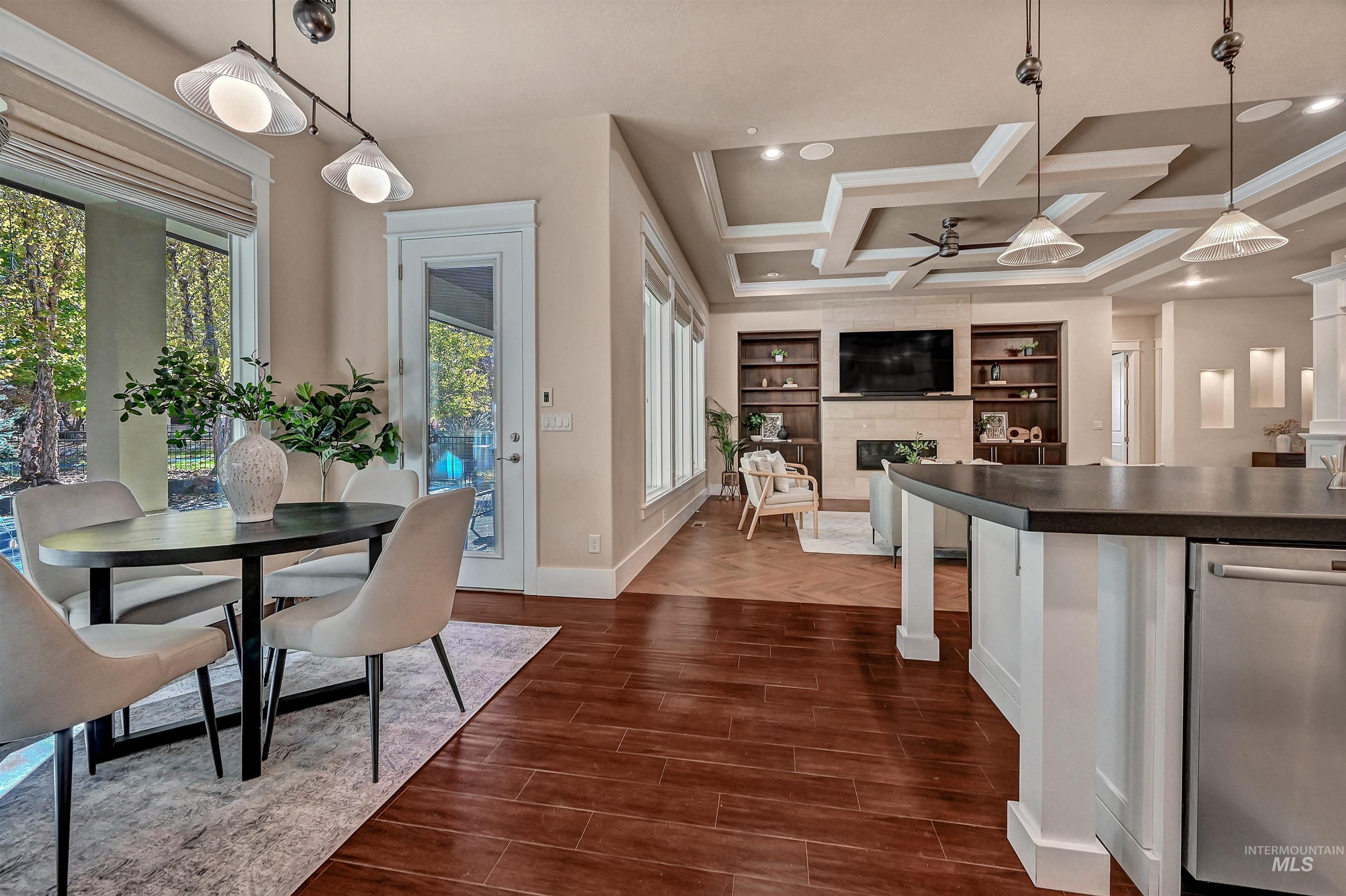 Kitchen with decorative light fixtures, stainless steel dishwasher, dark wood-style flooring, a premium fireplace, and coffered ceiling