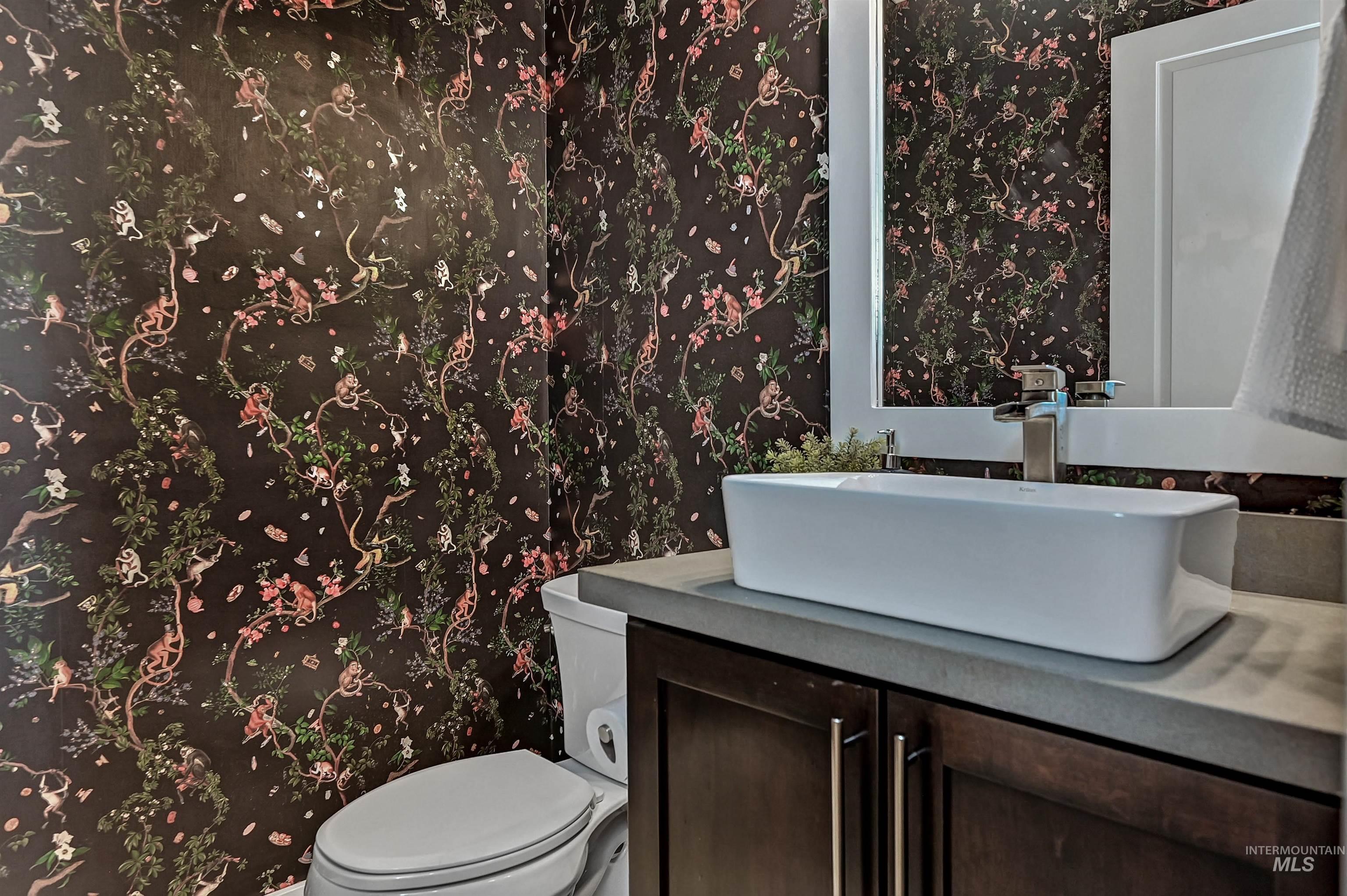 Half bath featuring wallpapered walls and vanity