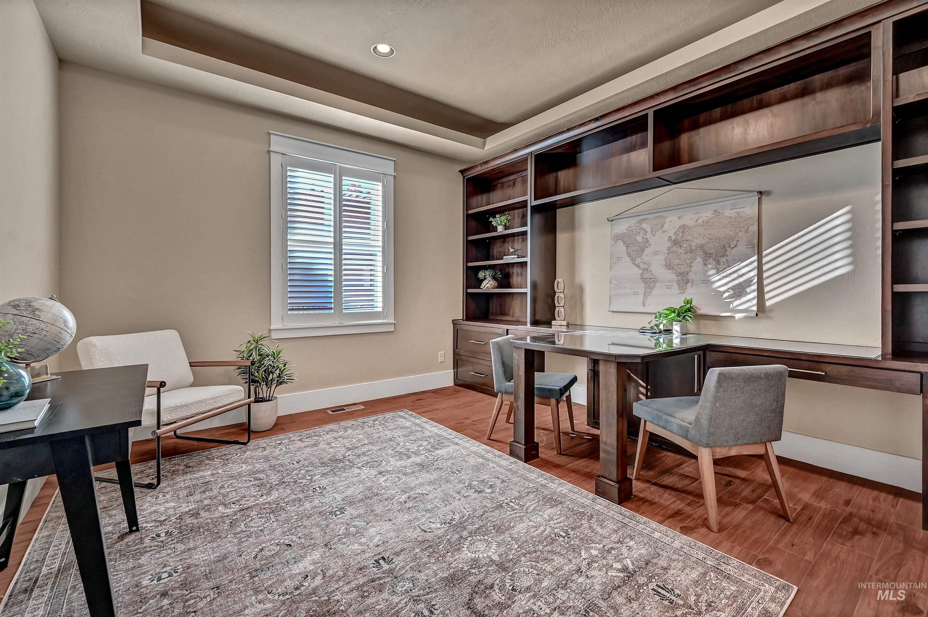 Office with a tray ceiling and light wood-style floors