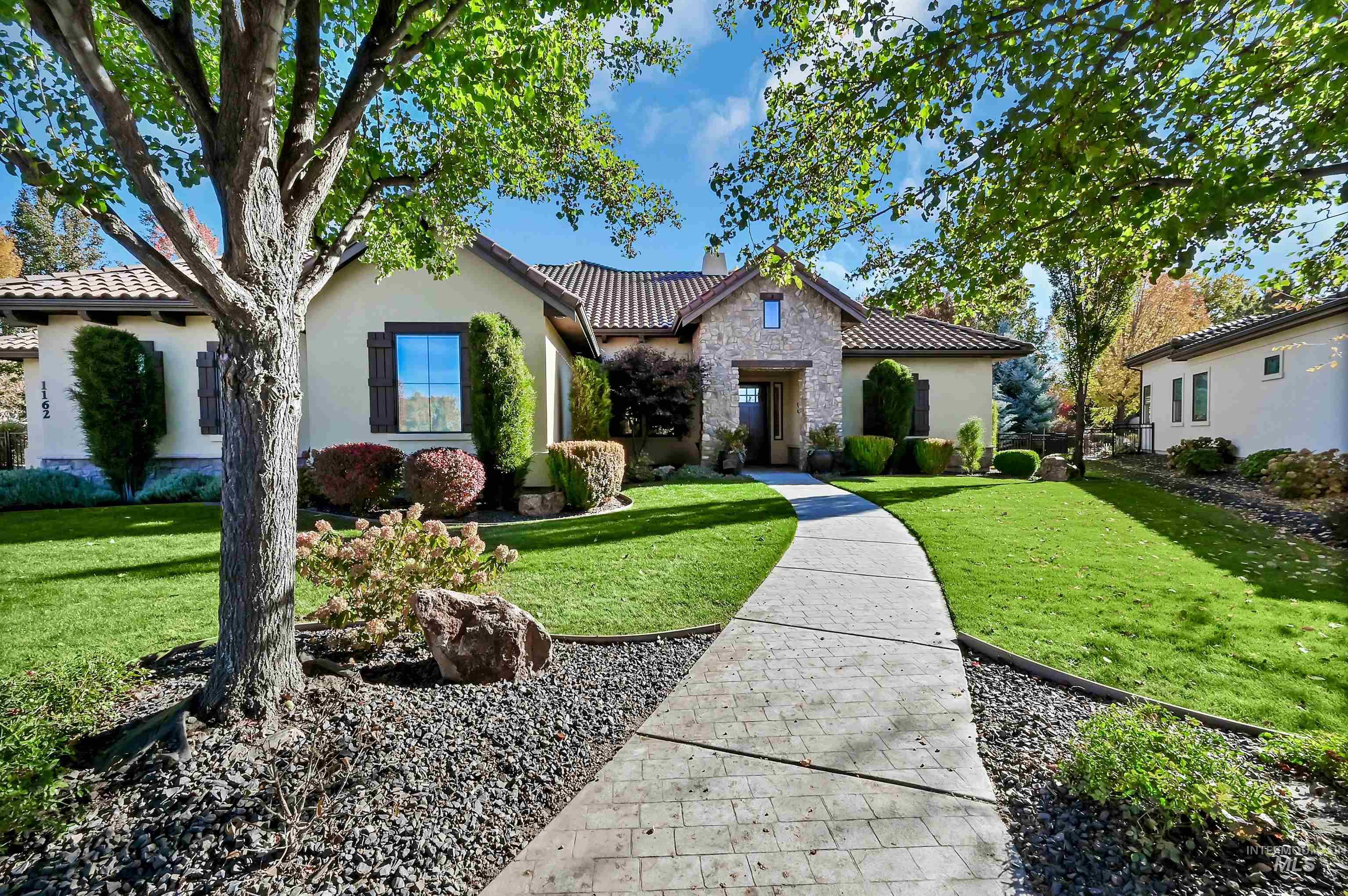 Mediterranean / spanish home featuring a front lawn, stucco siding, a tiled roof, and stone siding