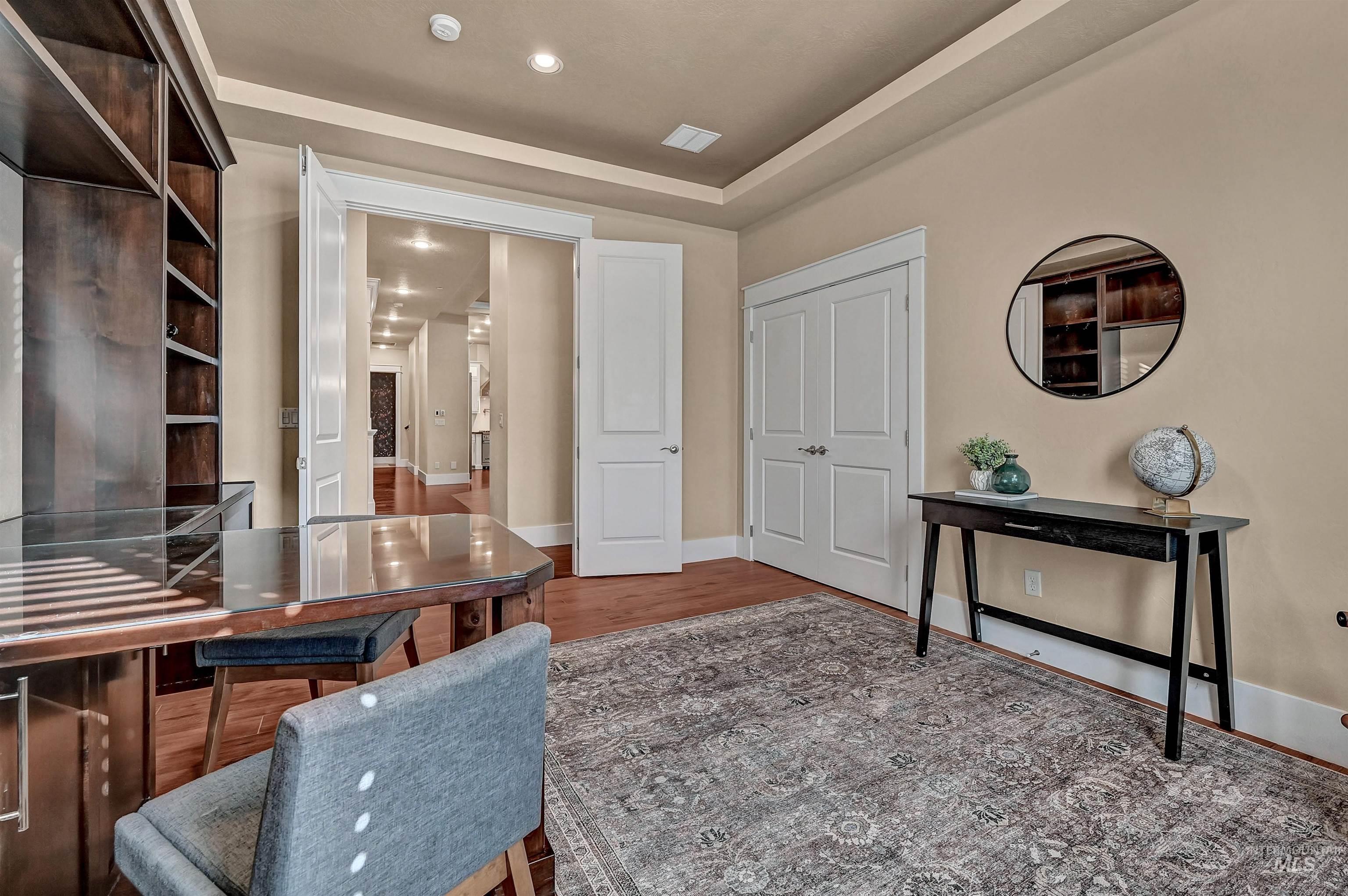 Office space featuring a raised ceiling, wood finished floors, and recessed lighting