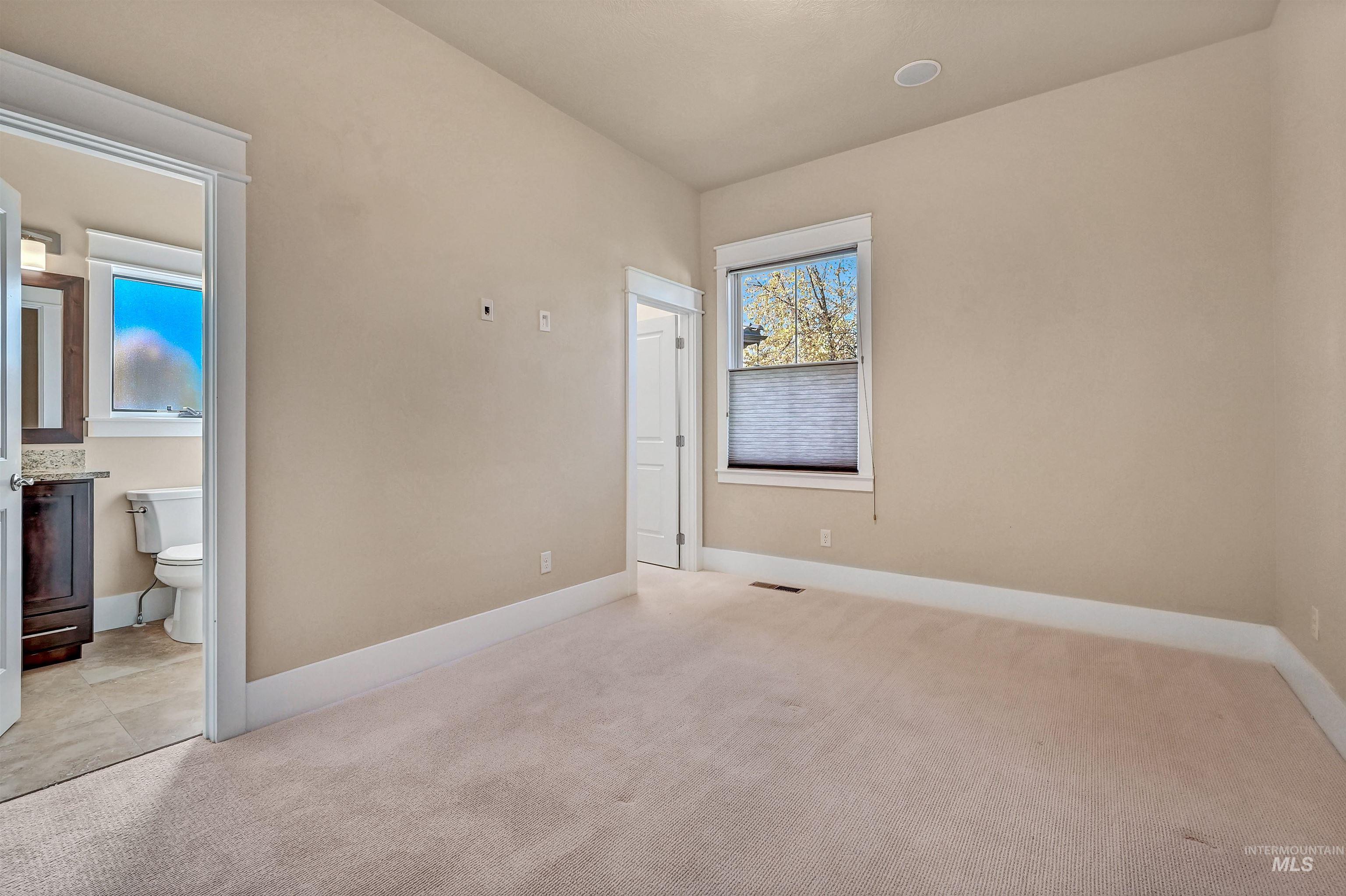 Unfurnished bedroom featuring light colored carpet and ensuite bath