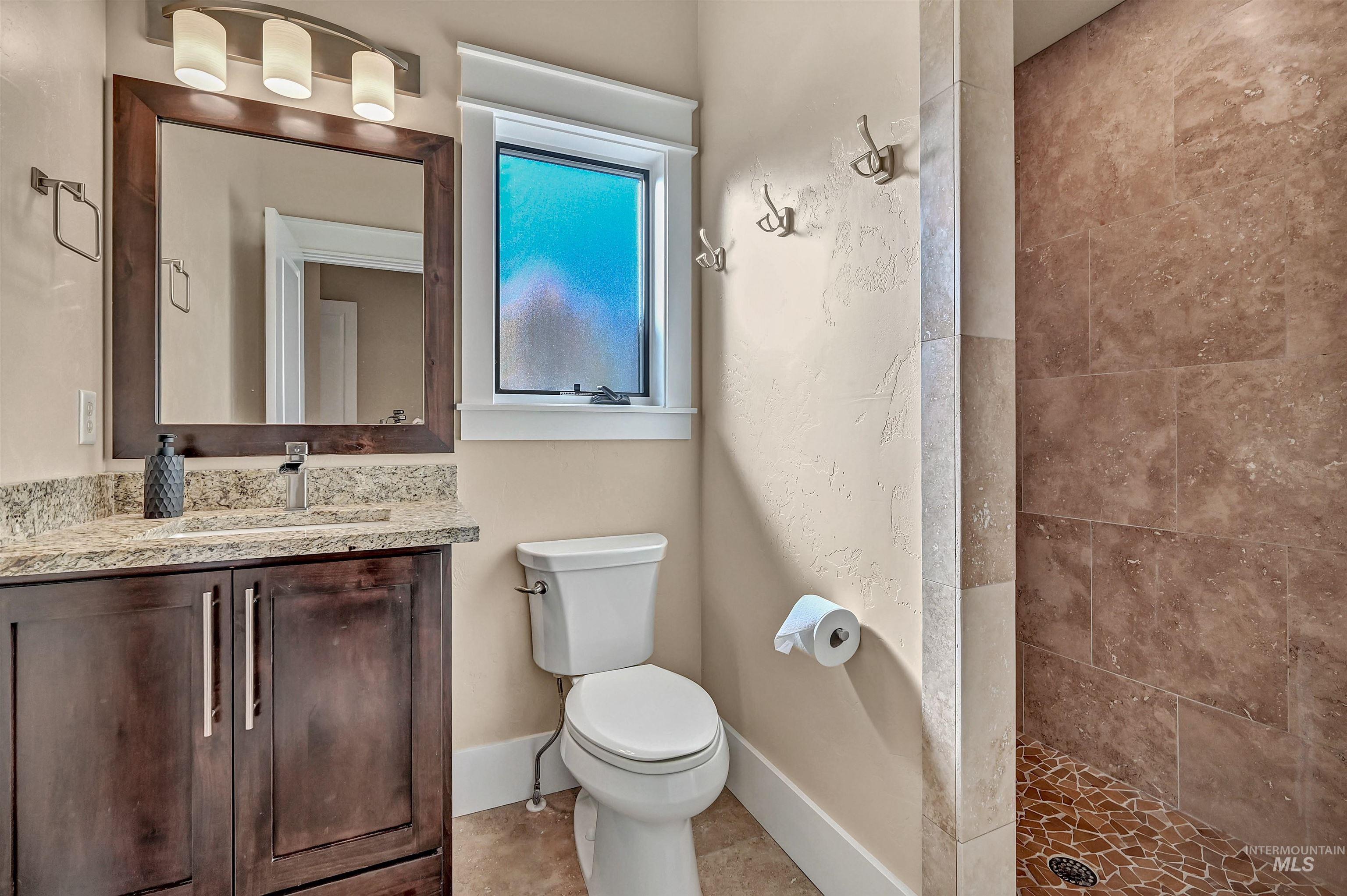 Bathroom with vanity, a tile shower, and light tile patterned floors