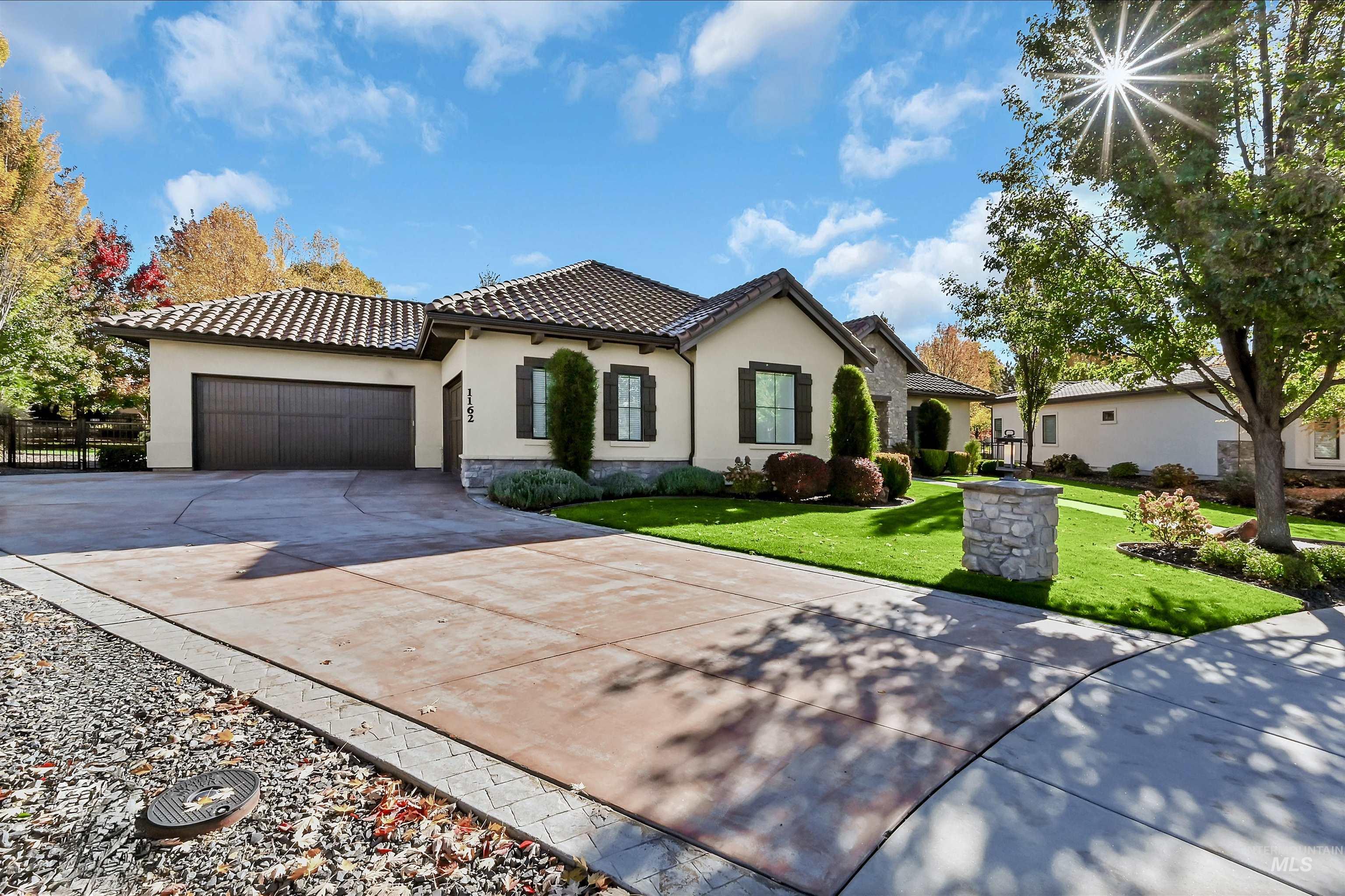 View of front of property featuring stucco siding, driveway, an attached garage, a tile roof, and a front yard