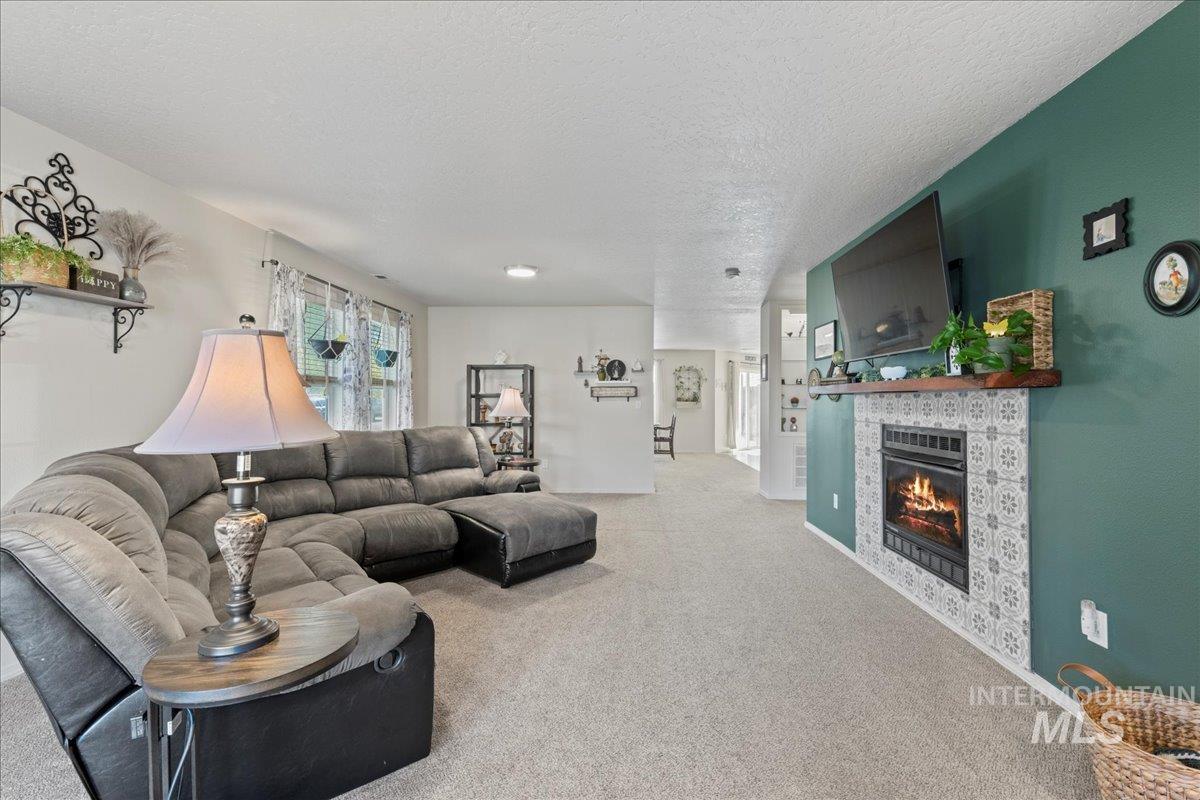 Carpeted living room featuring a tiled fireplace and a textured ceiling