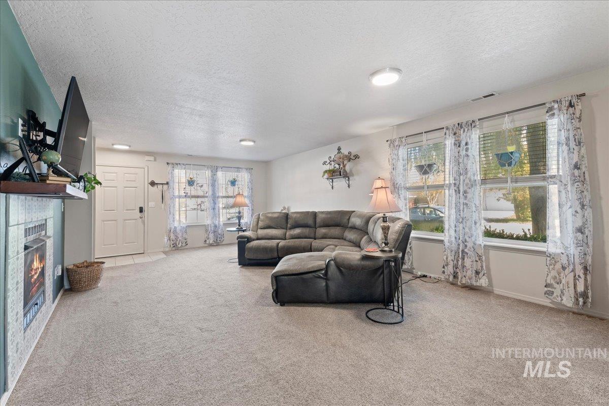 Living room with light carpet, a fireplace, and a textured ceiling