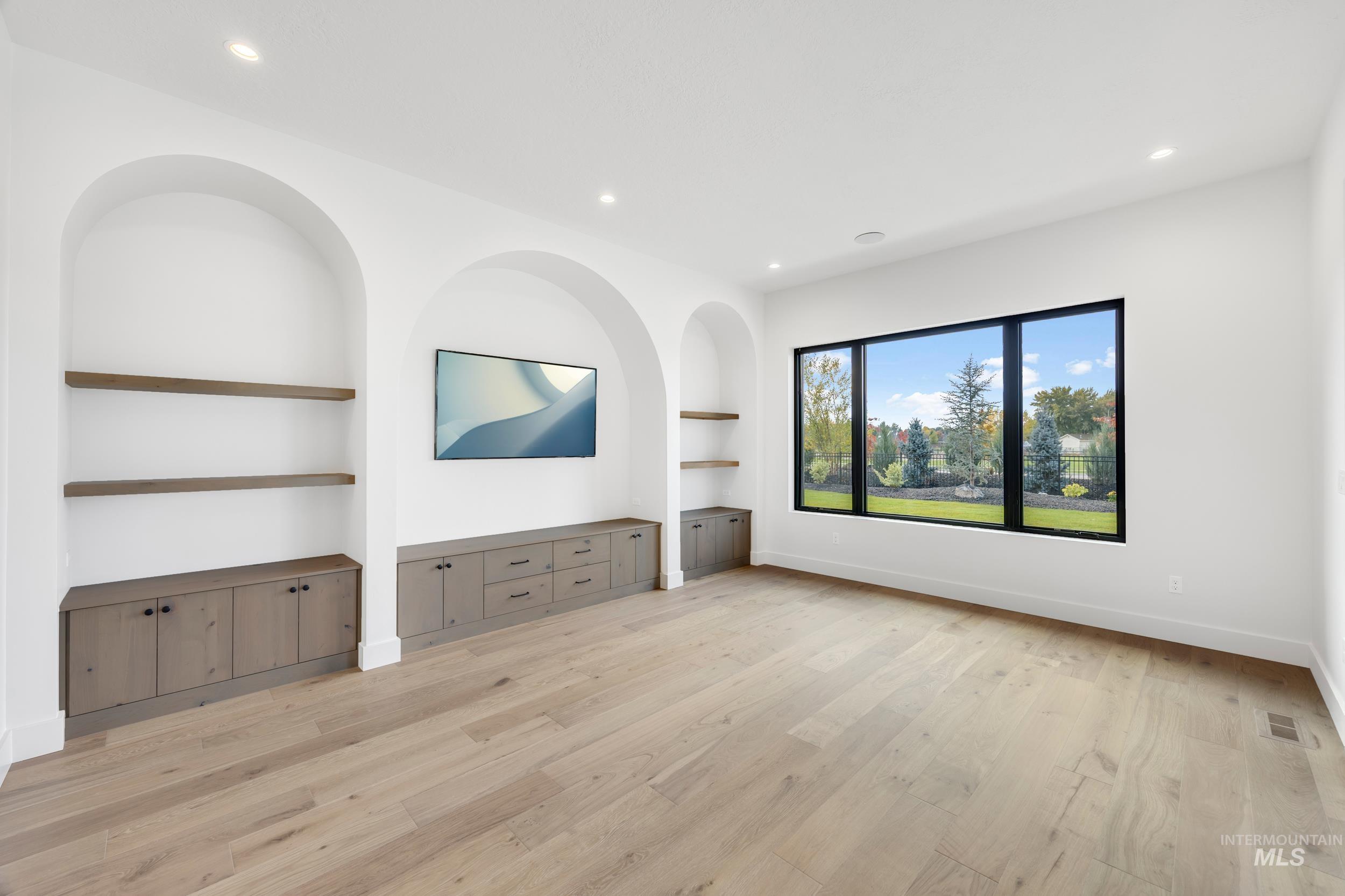 Unfurnished living room featuring built in shelves, recessed lighting, and light wood-type flooring