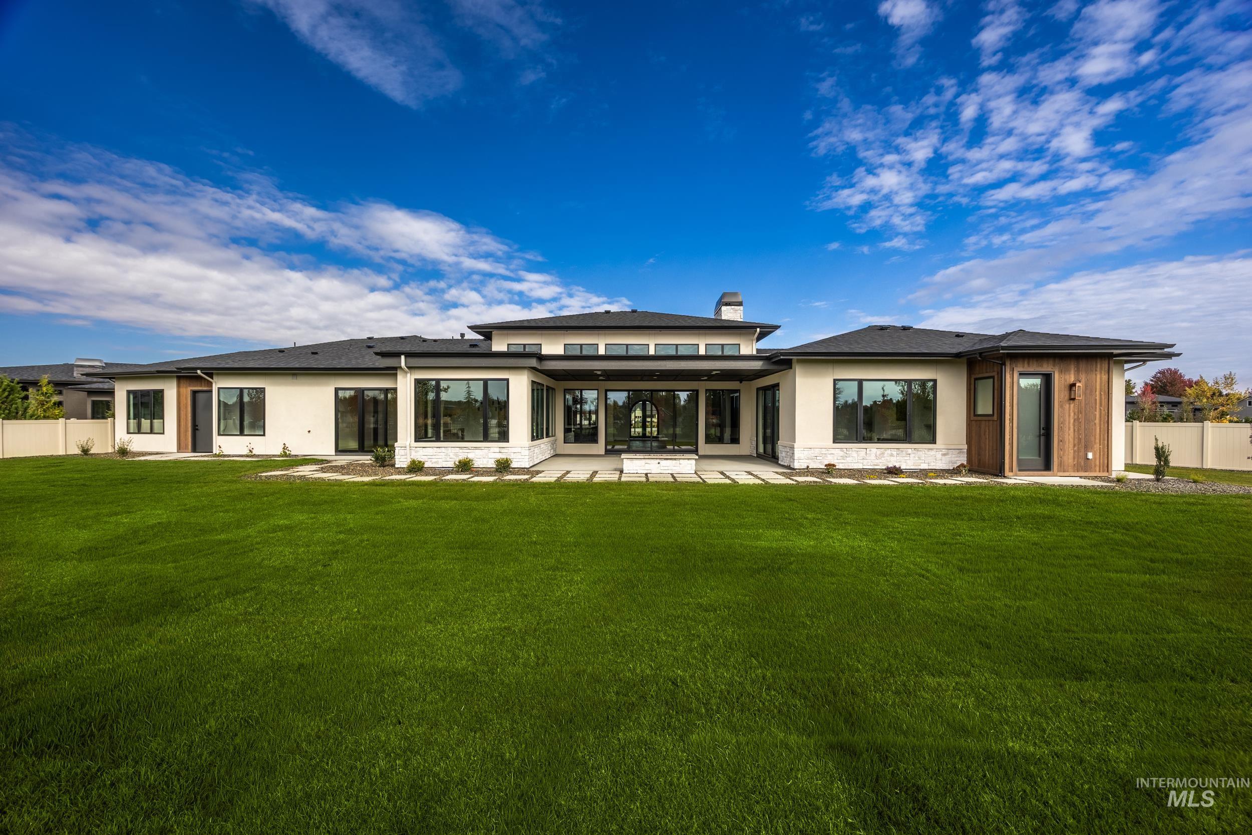 Back of house featuring stone siding, a patio, a chimney, and stucco siding