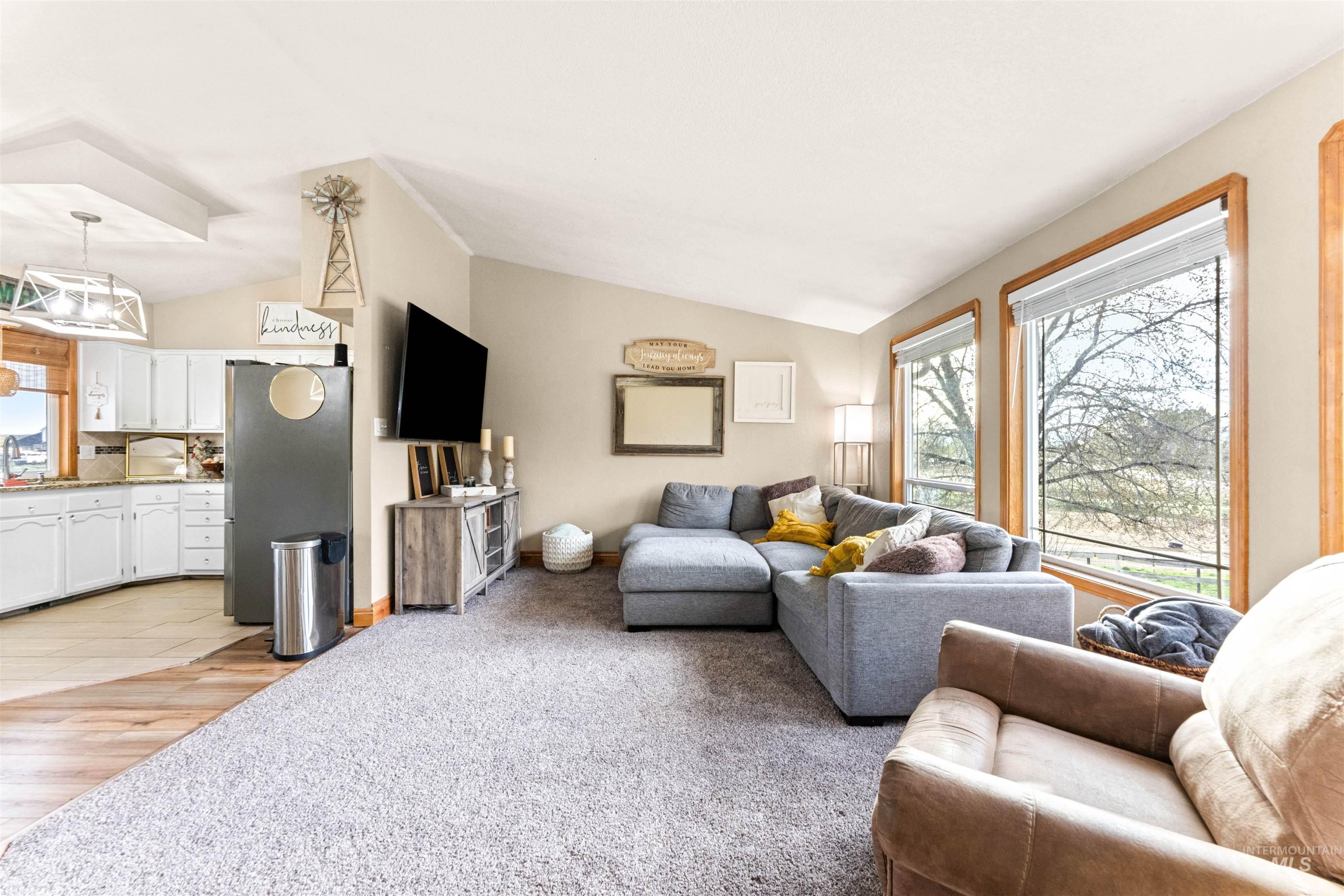 Living area with plenty of natural light, lofted ceiling, light colored carpet, and light wood-style flooring