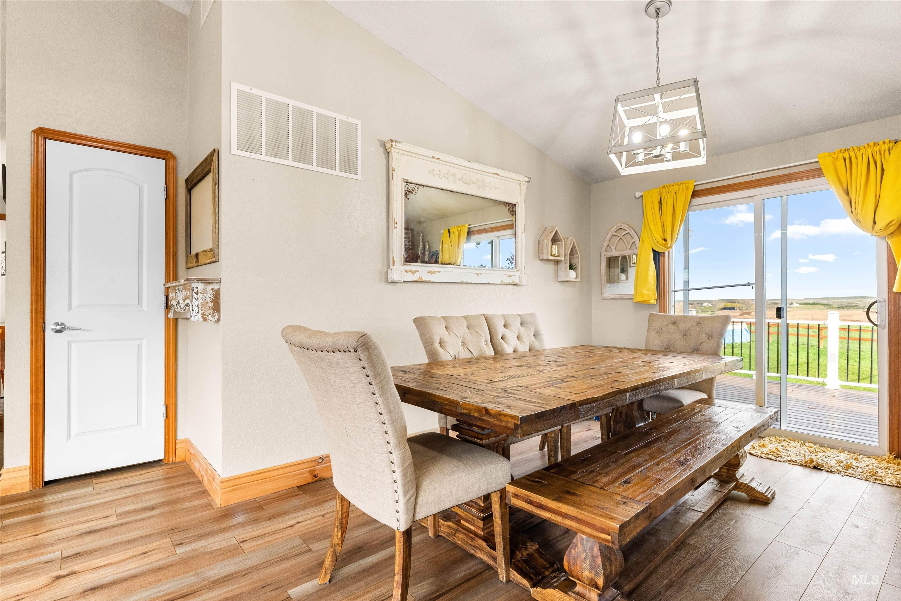 Dining room with lofted ceiling, light wood-style floors, and a chandelier
