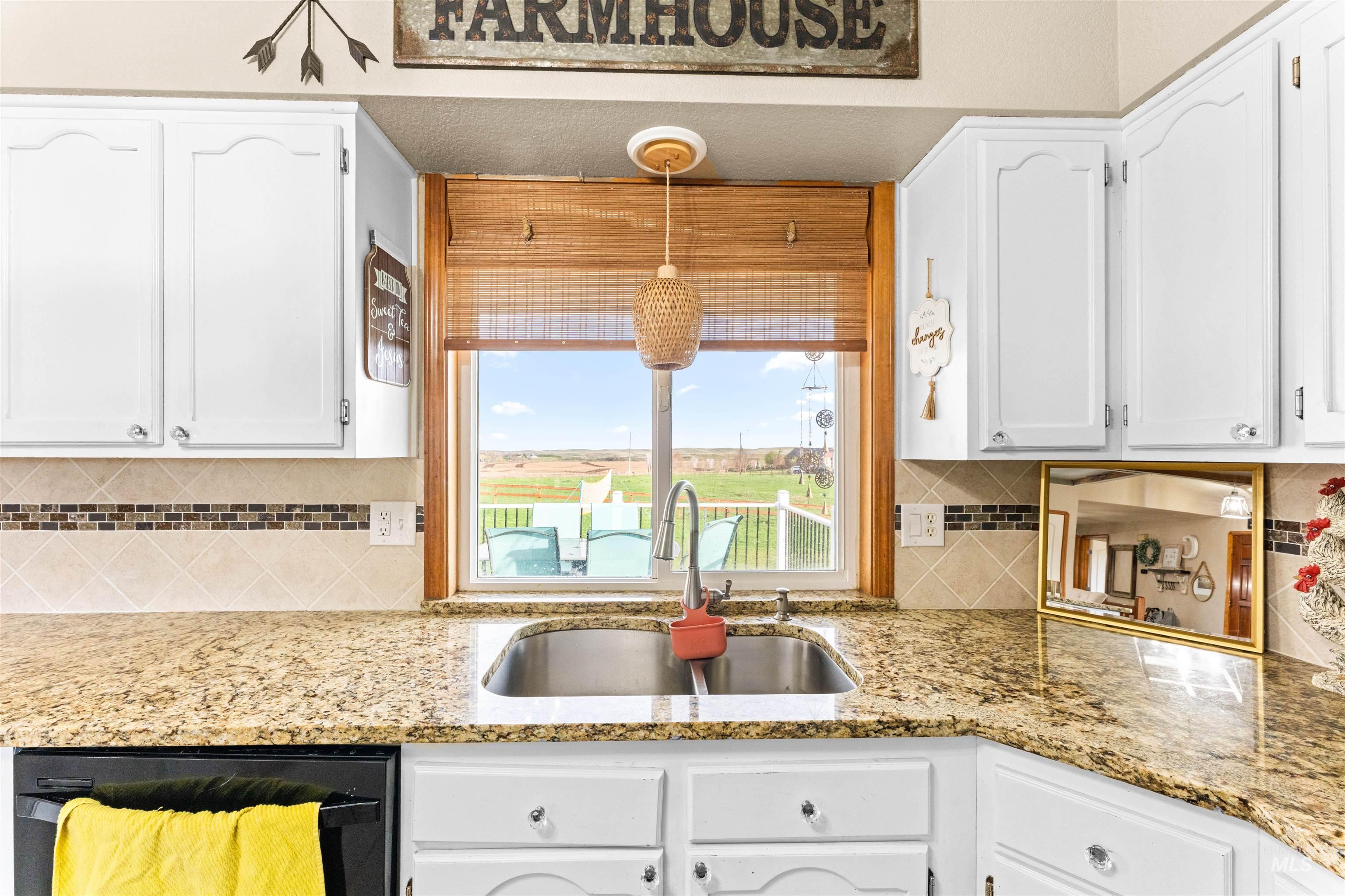 Kitchen featuring white cabinetry, dishwasher, decorative light fixtures, and light stone countertops