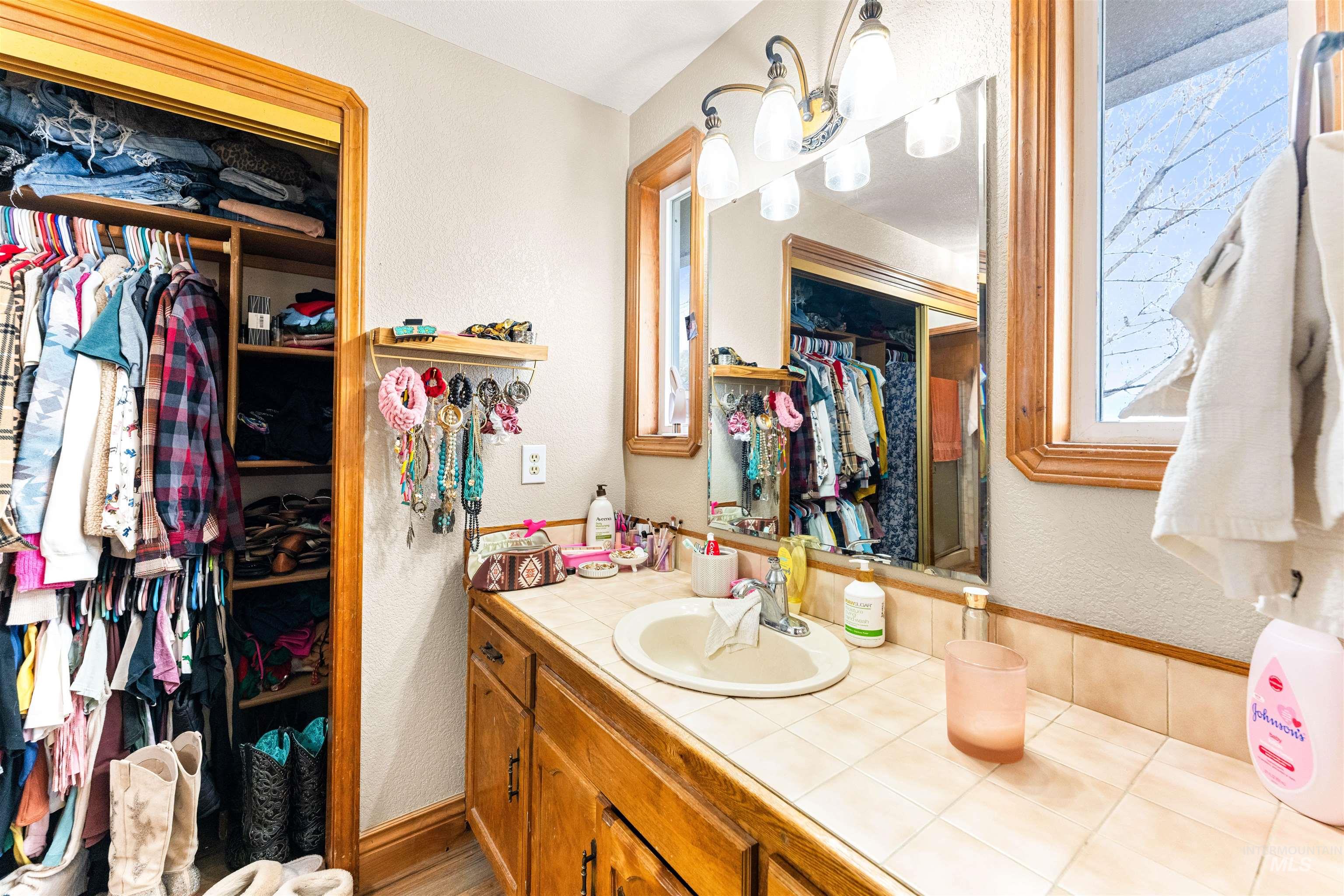 Bathroom with a spacious closet, a textured wall, and vanity