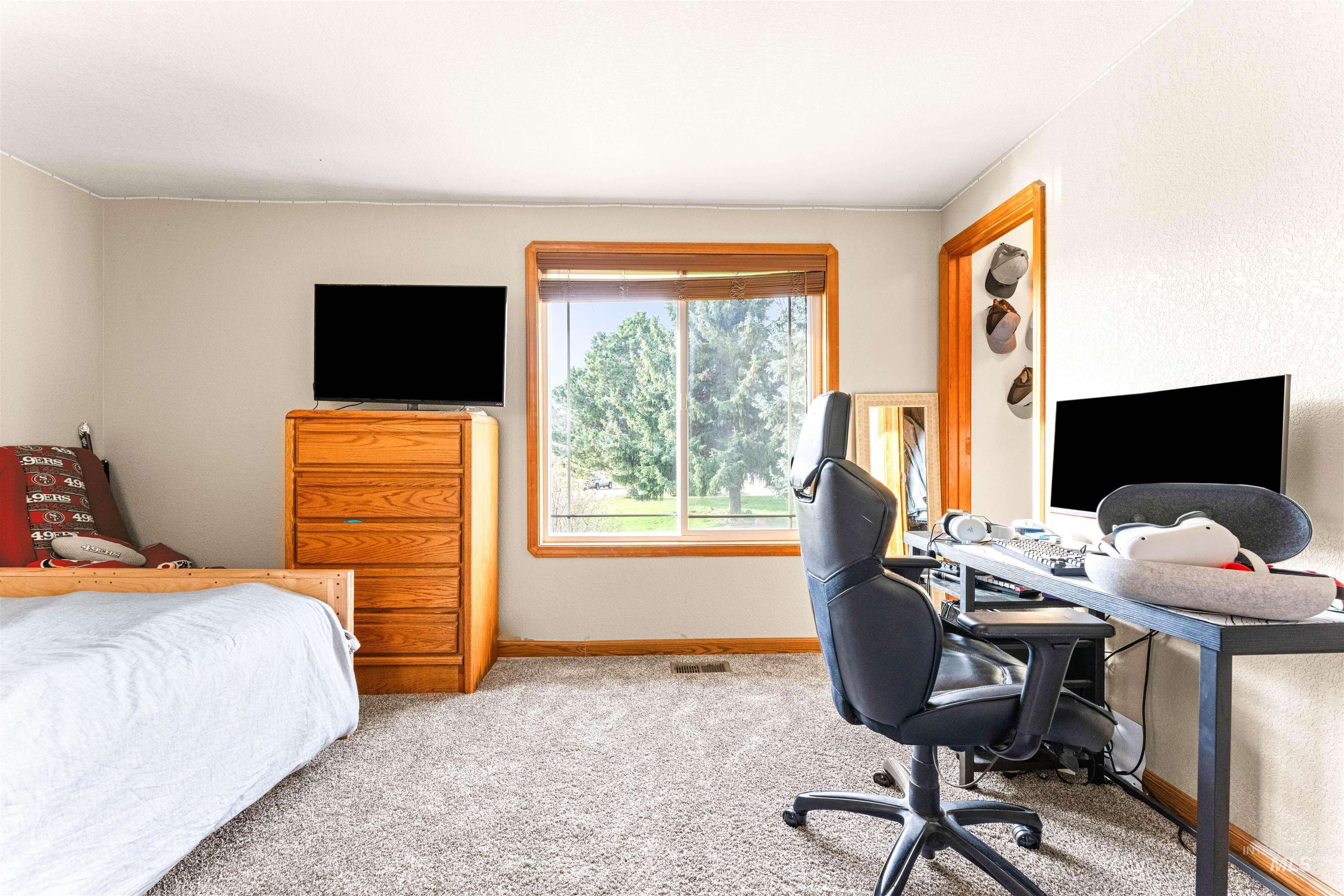Carpeted bedroom with baseboards and a desk