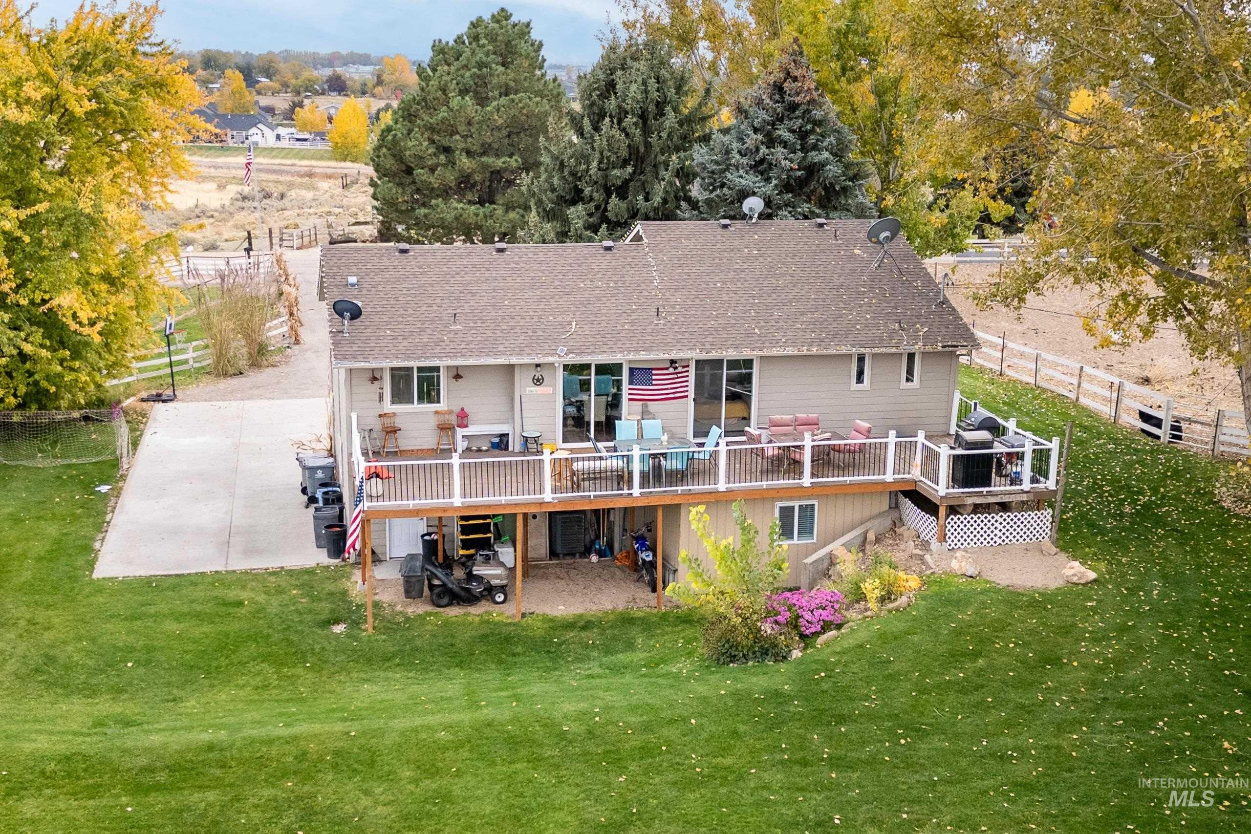 Back of house featuring a deck, roof with shingles, and a patio