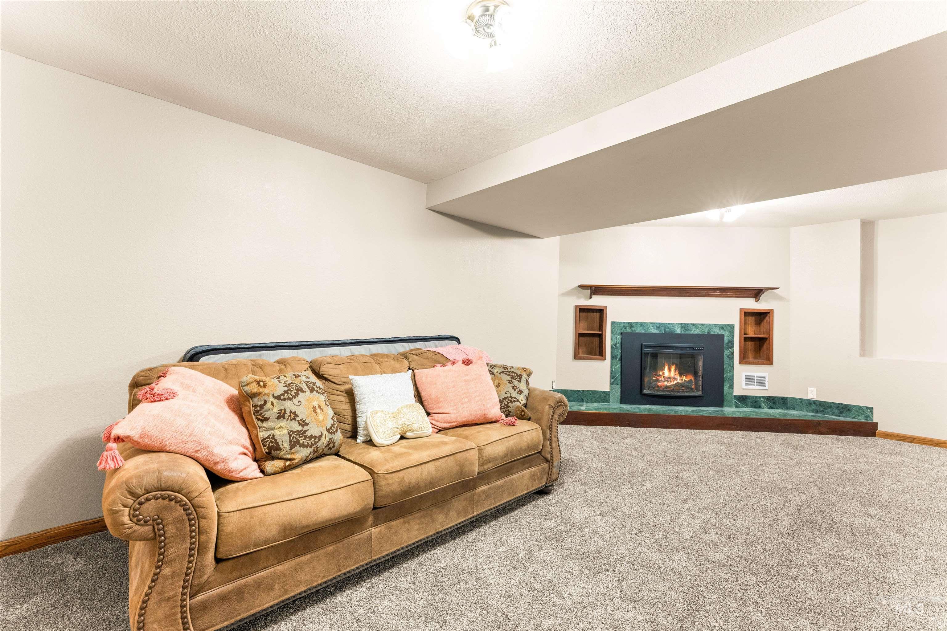 Carpeted living room with a high end fireplace and a textured ceiling