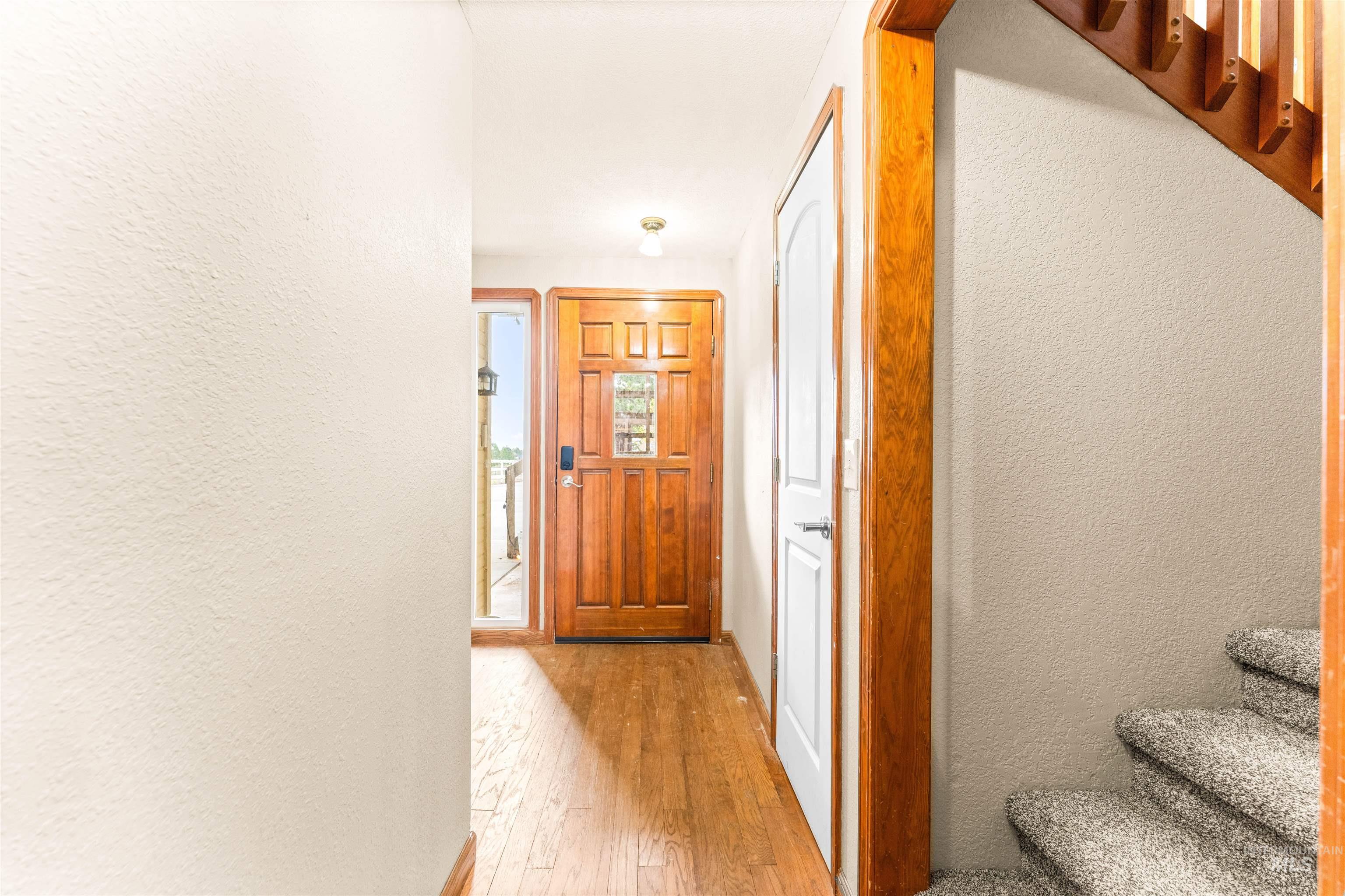 Hall featuring a textured wall, light wood-type flooring, and stairs