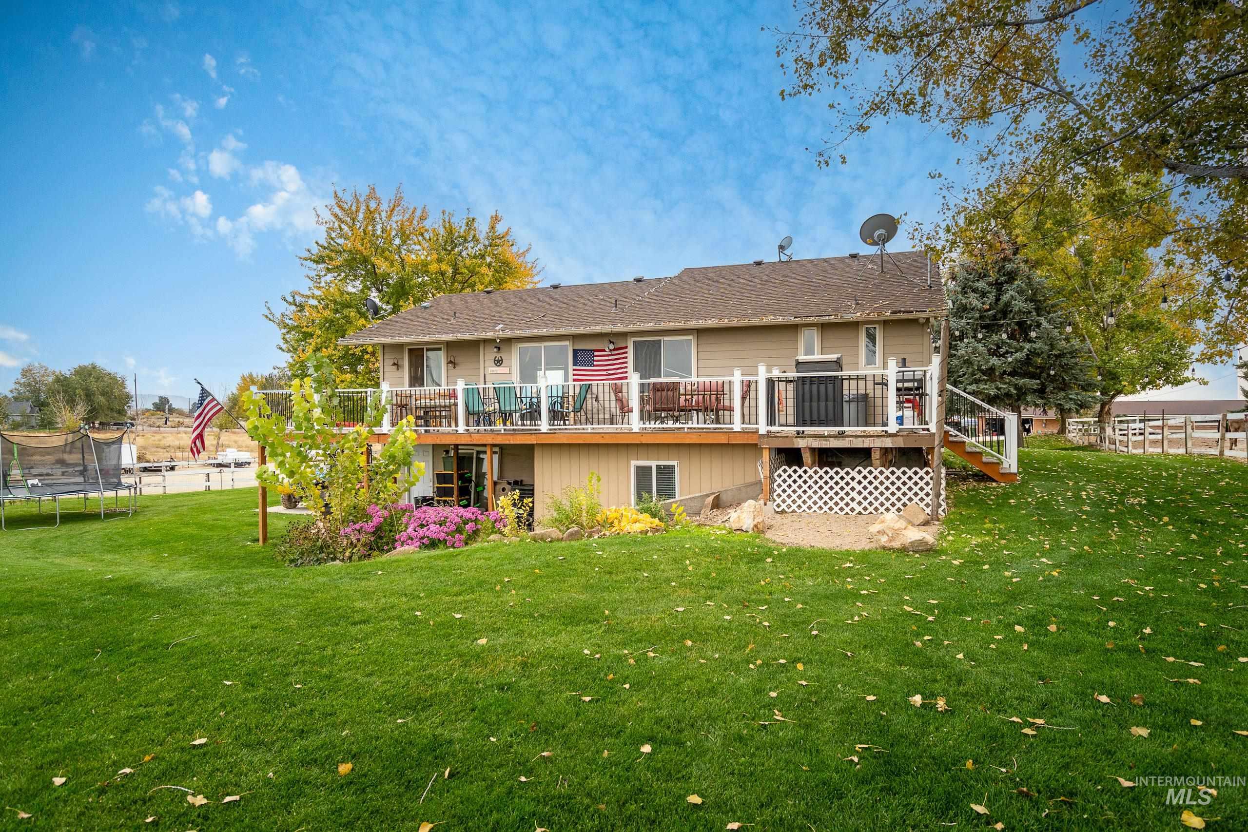 Rear view of house with a trampoline, a wooden deck, and stairs