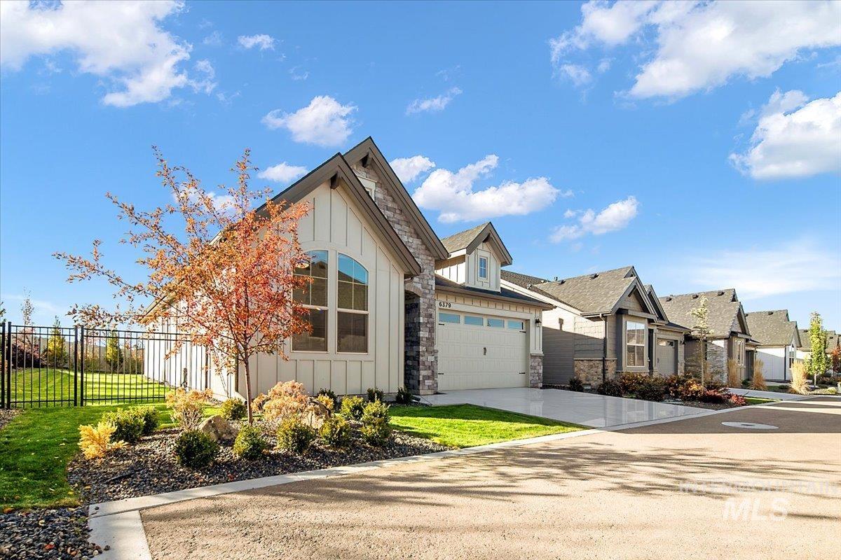 View of front of property with board and batten siding, stone siding, concrete driveway, a residential view, and an attached garage