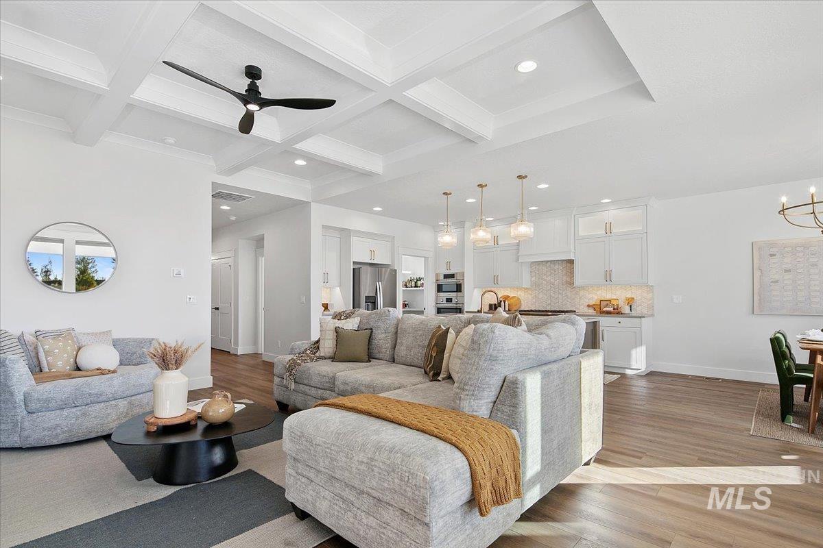 Living area featuring light wood-style flooring, beam ceiling, recessed lighting, coffered ceiling, and a chandelier