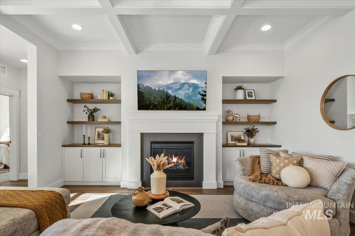 Living area featuring recessed lighting, beamed ceiling, built in features, a glass covered fireplace, and wood finished floors