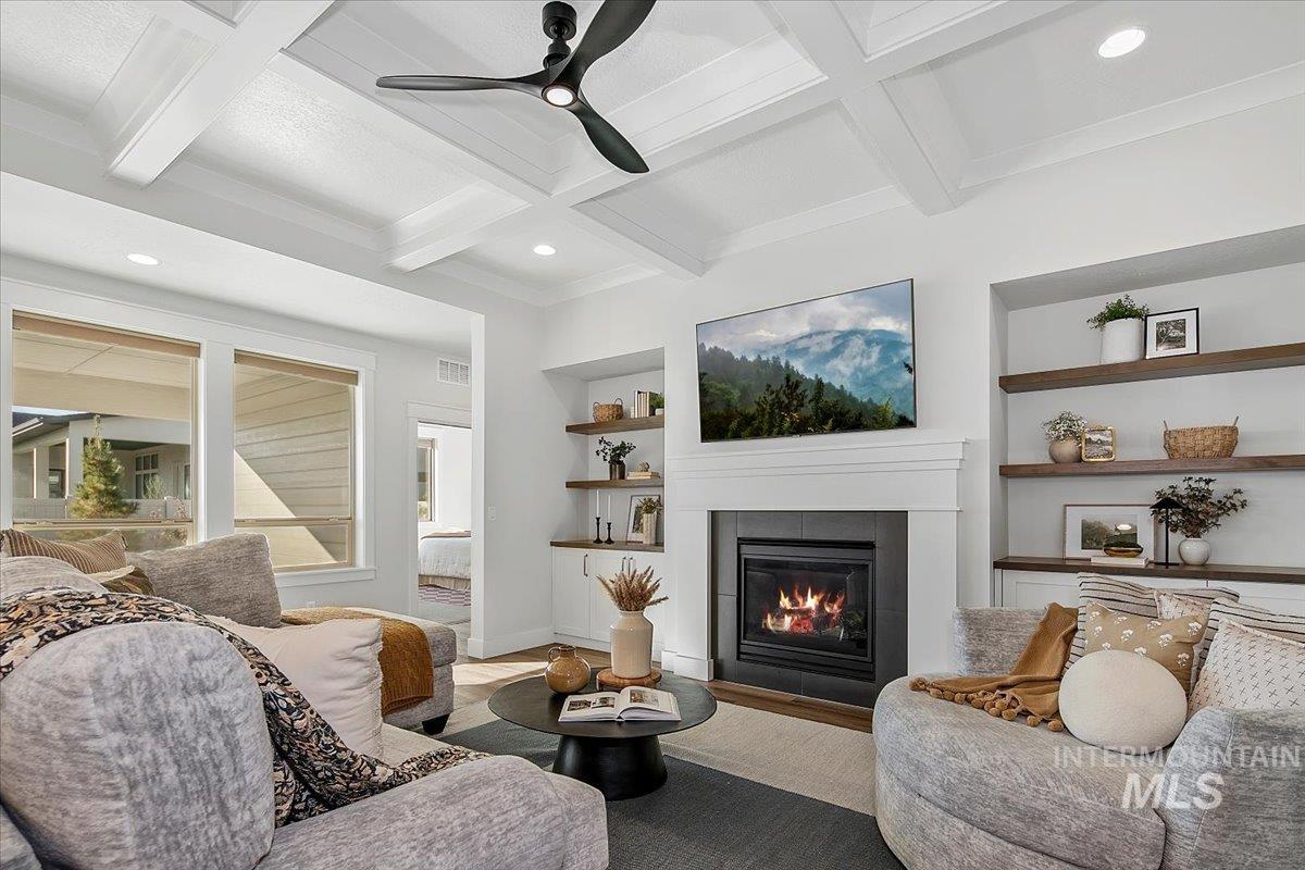 Living area featuring built in shelves, beamed ceiling, a fireplace, recessed lighting, and ceiling fan