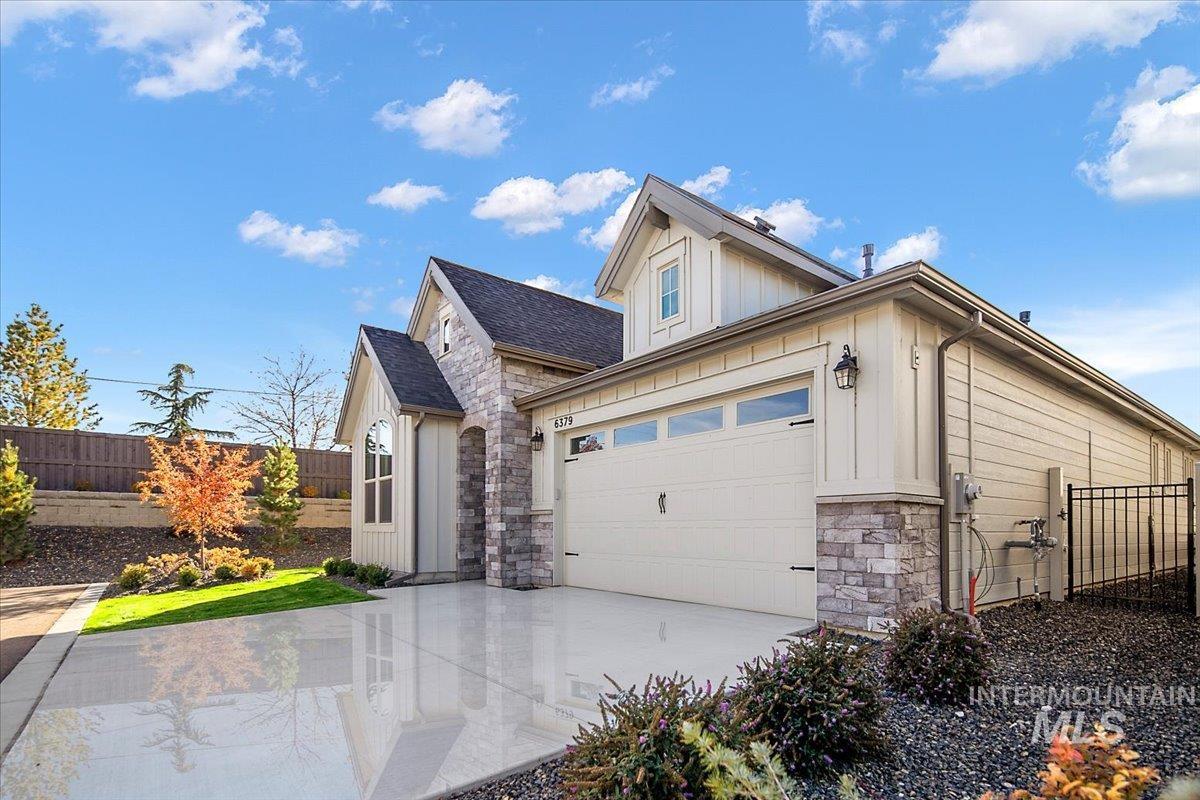 View of front of property featuring board and batten siding, stone siding, driveway, and a garage